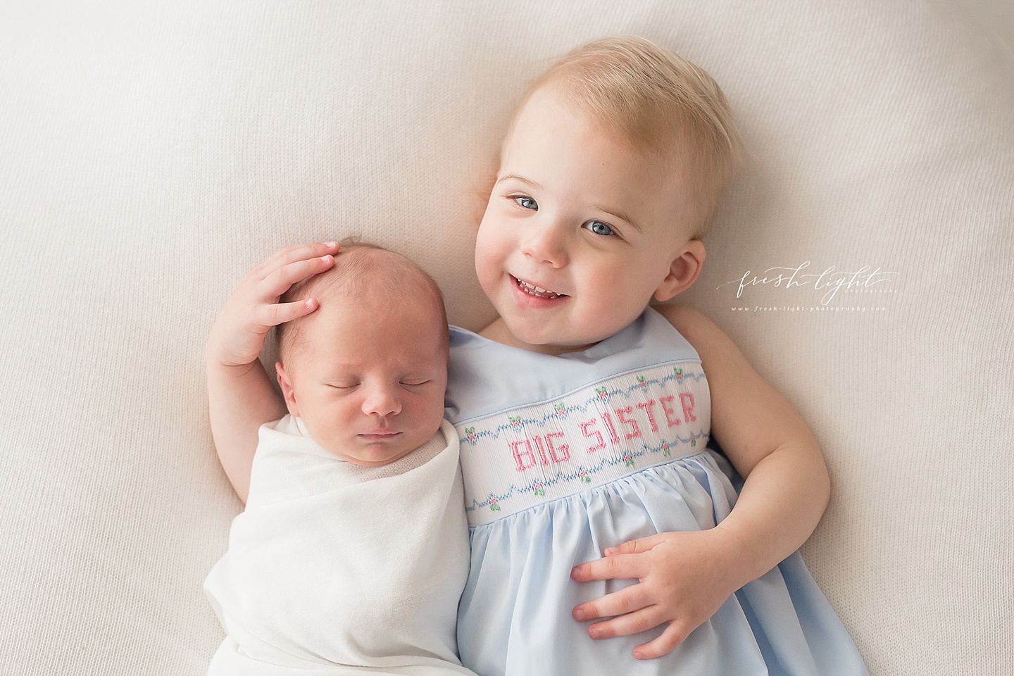 big sister with newborn brother on white