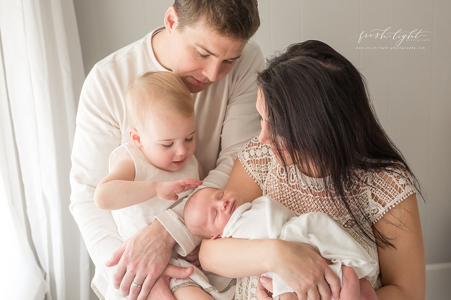 family picture with newborn and sister touching brother's head
