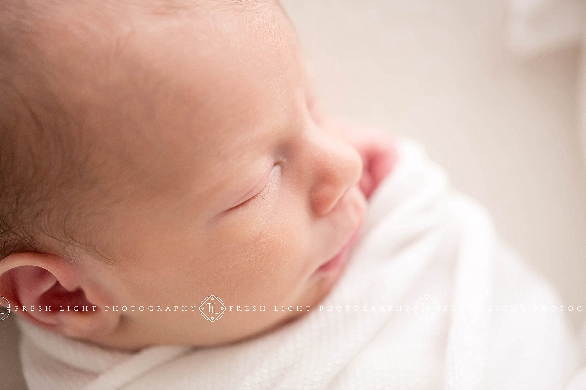 Close up of a newborn's face in a white blanket in houston