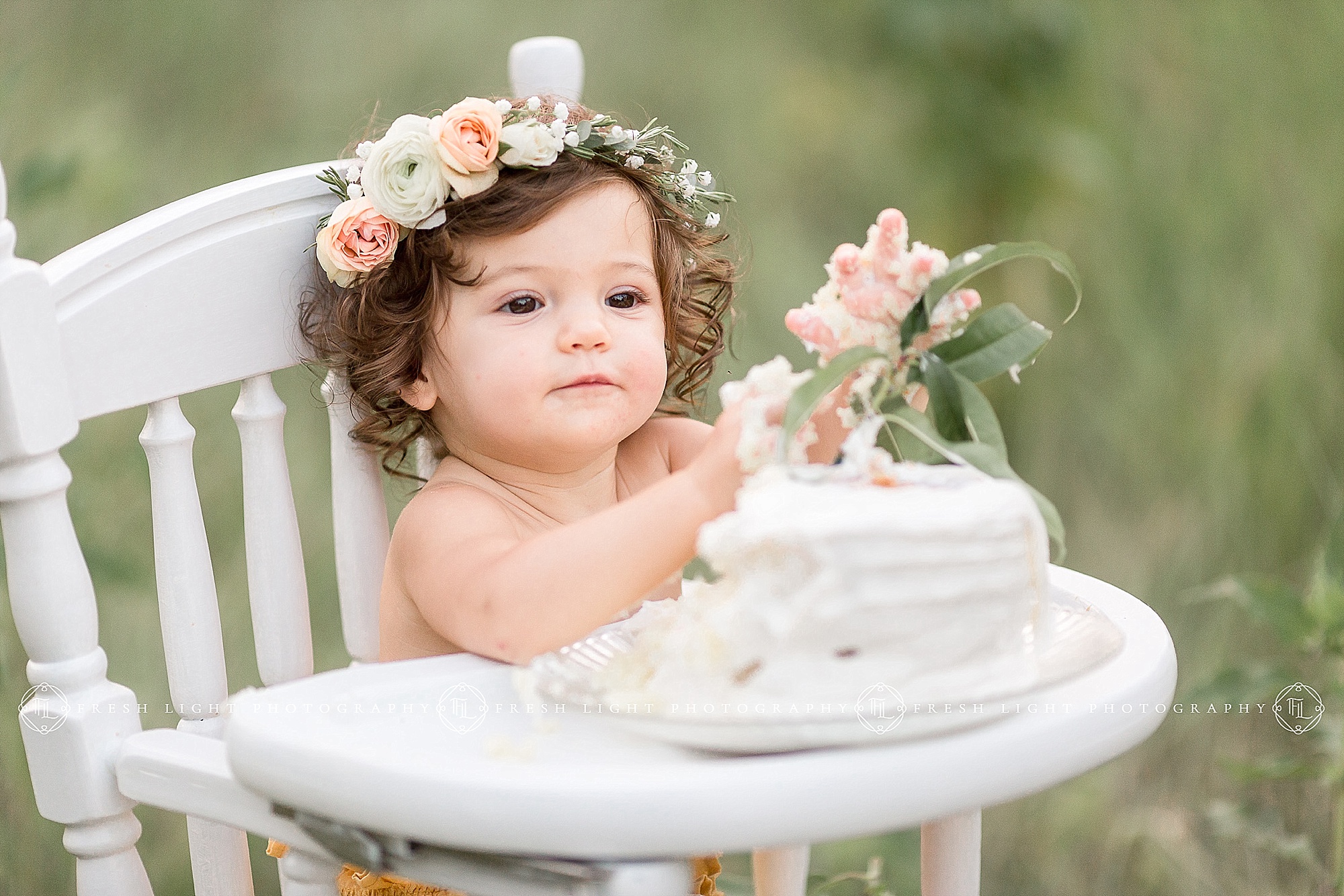 Baby in high chair eating cake
