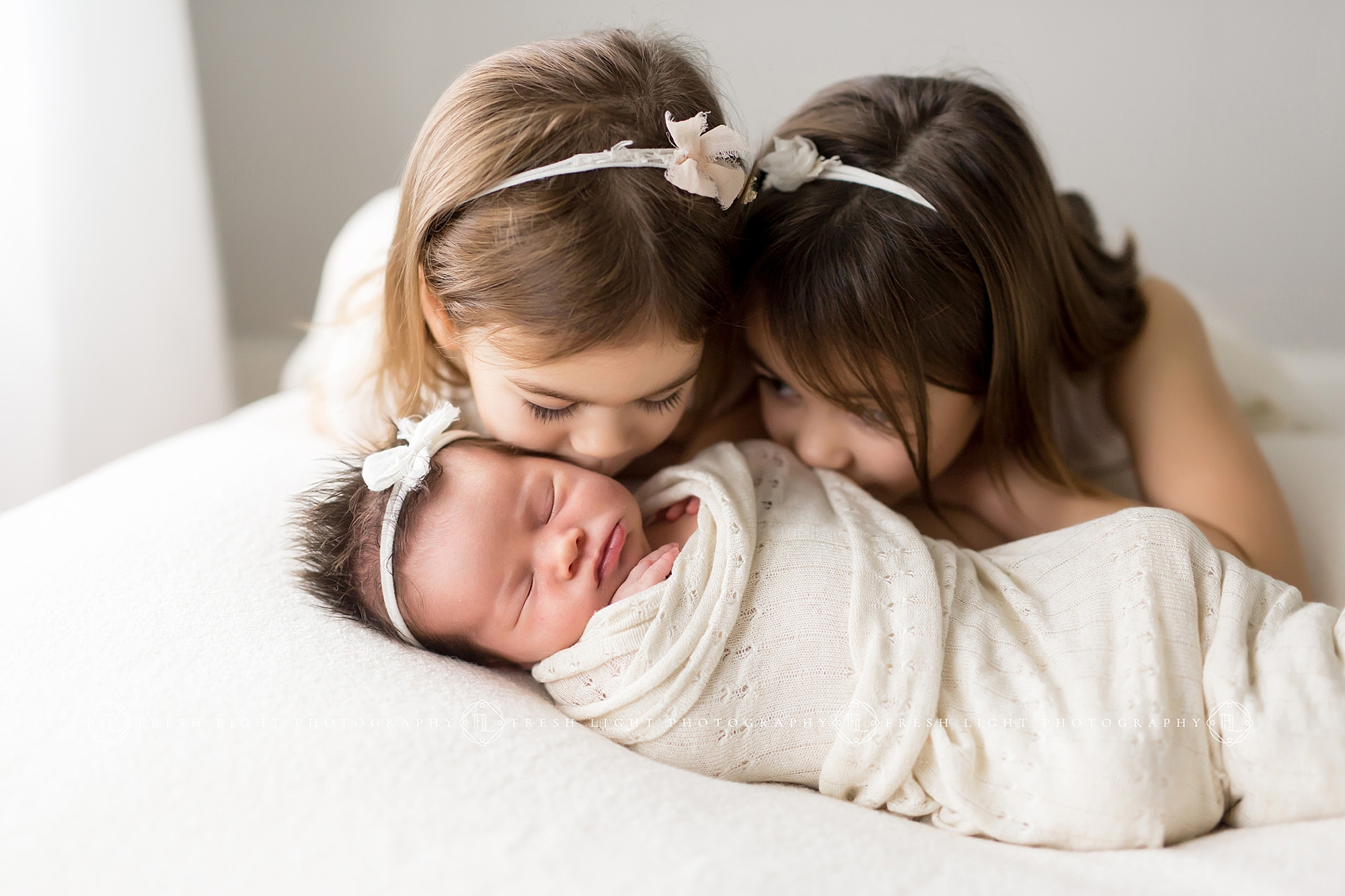 sisters kissing their new baby sister
