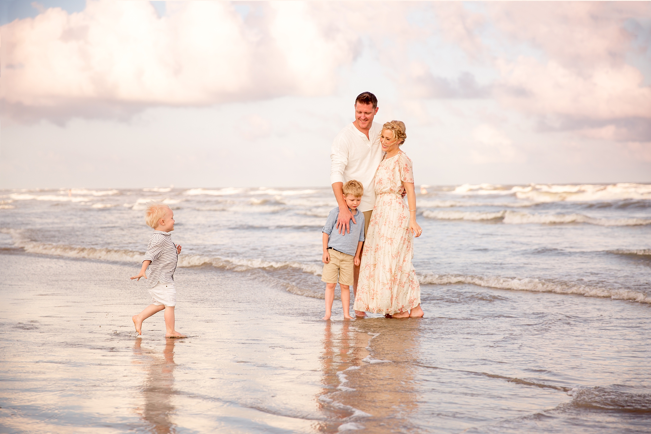 puffy white clouds over family on the beach