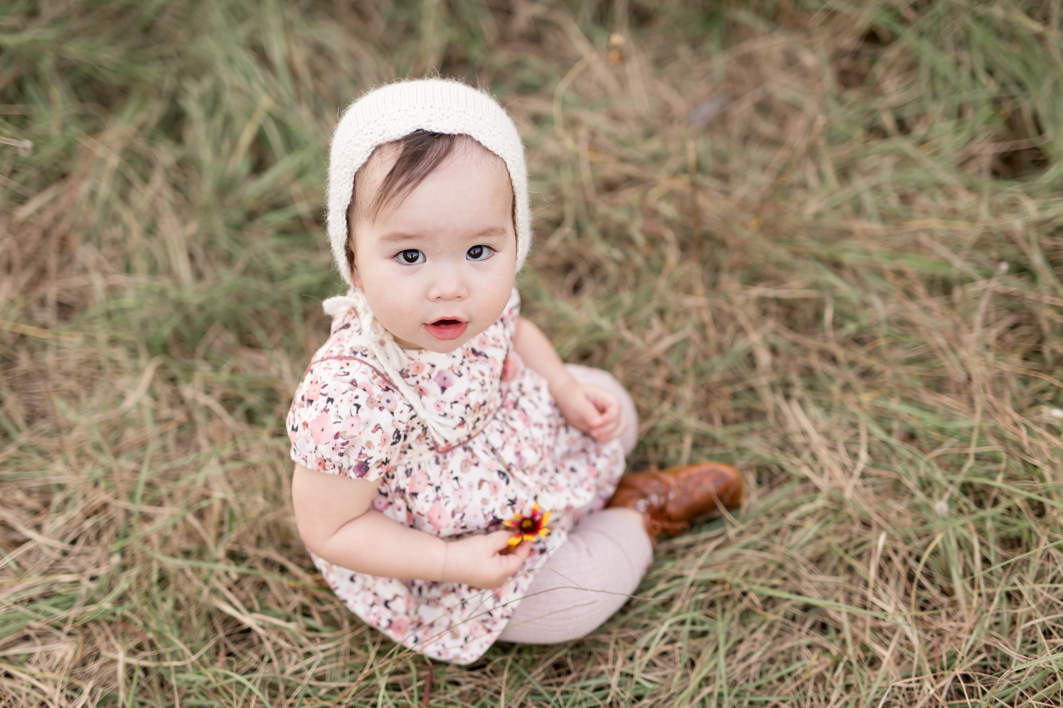 baby in bonnet sitting in grass