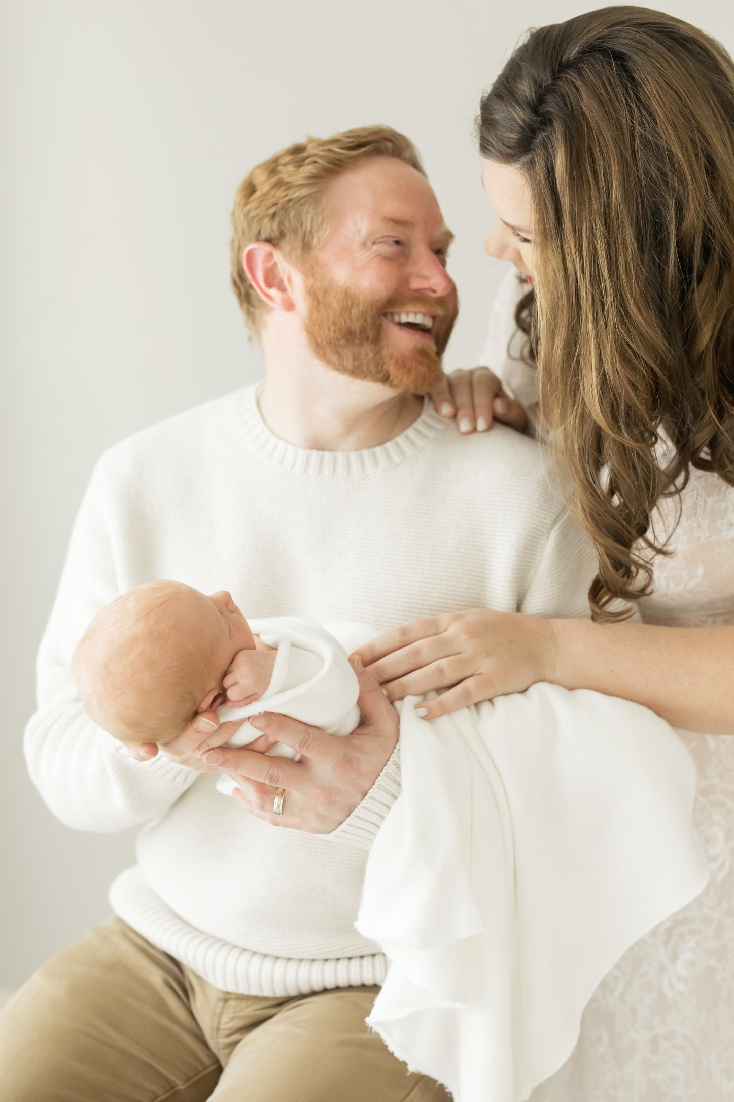 couple laughing while holding new baby