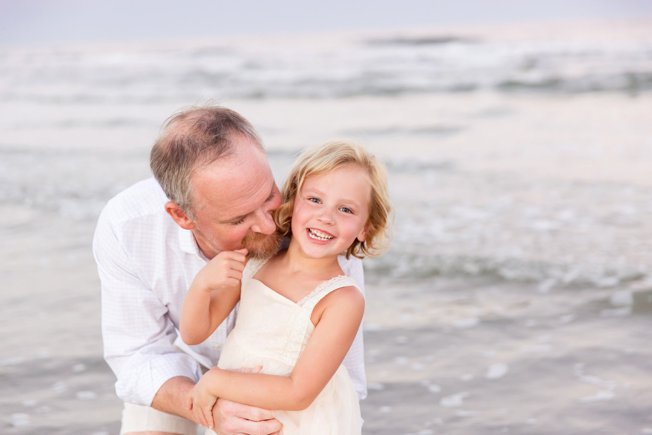 dad kissing daughter on the beach