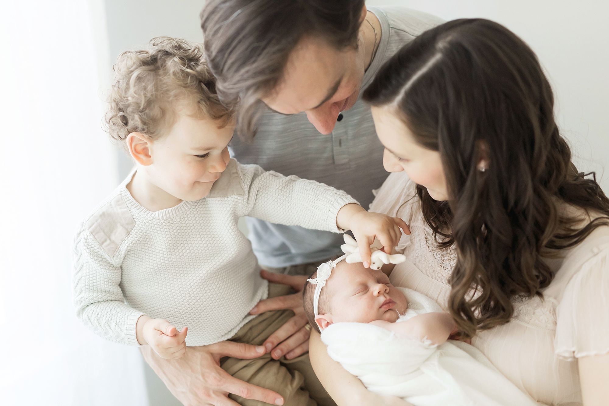 brother showing new baby sister a toy