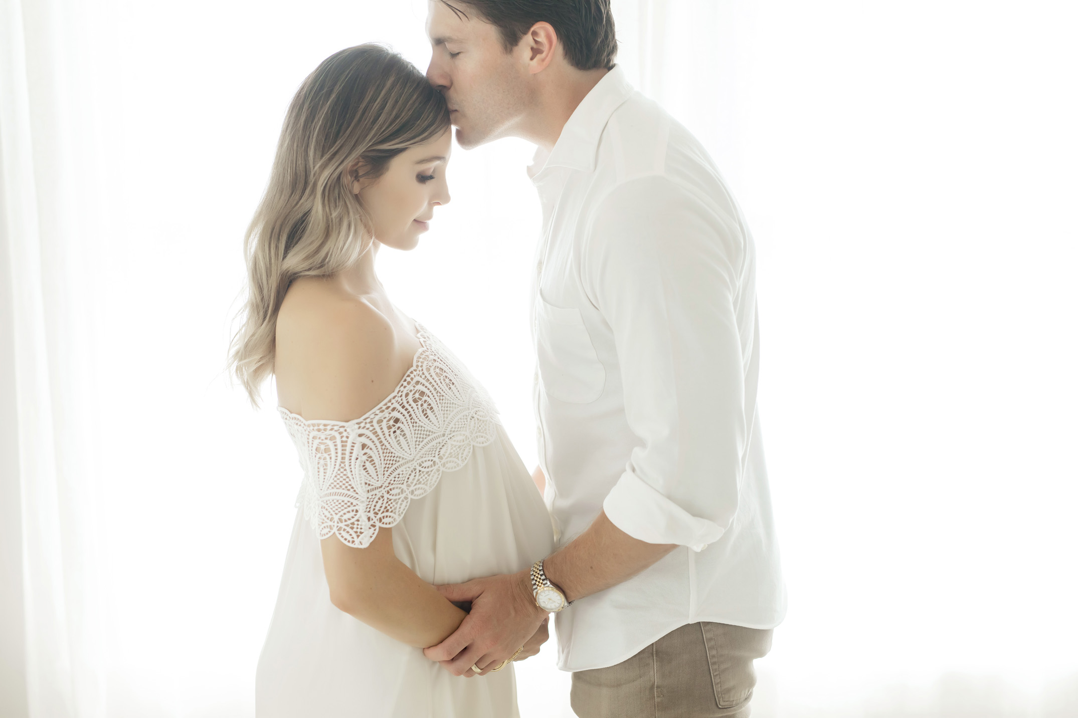 husband kissing wife's head during their maternity pictures with fresh light photography in Houston