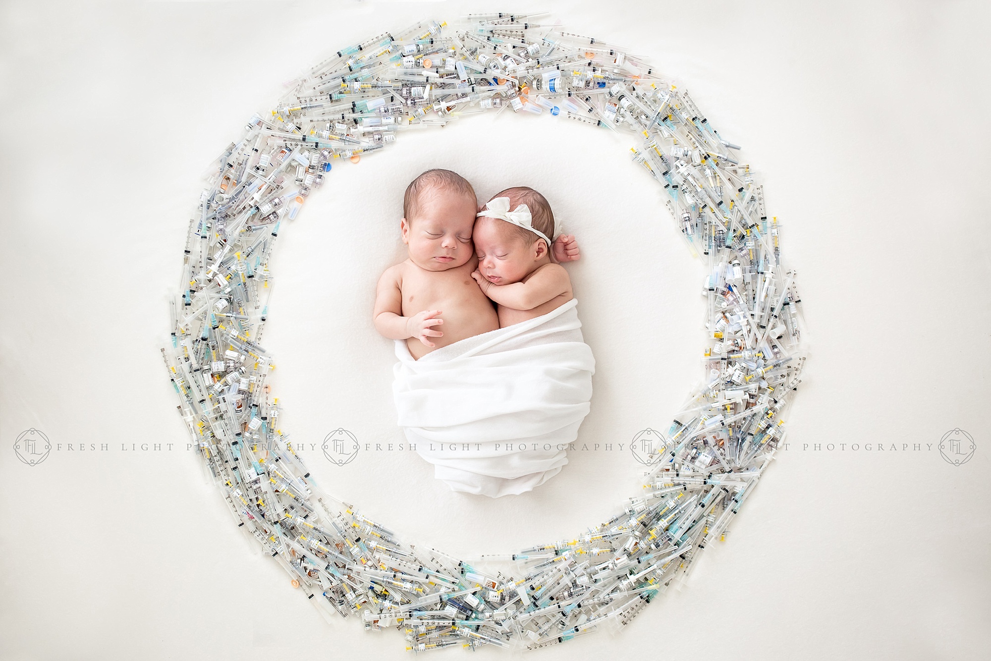 Newborn Twins surrounded by a infertility syringe wreath IVF