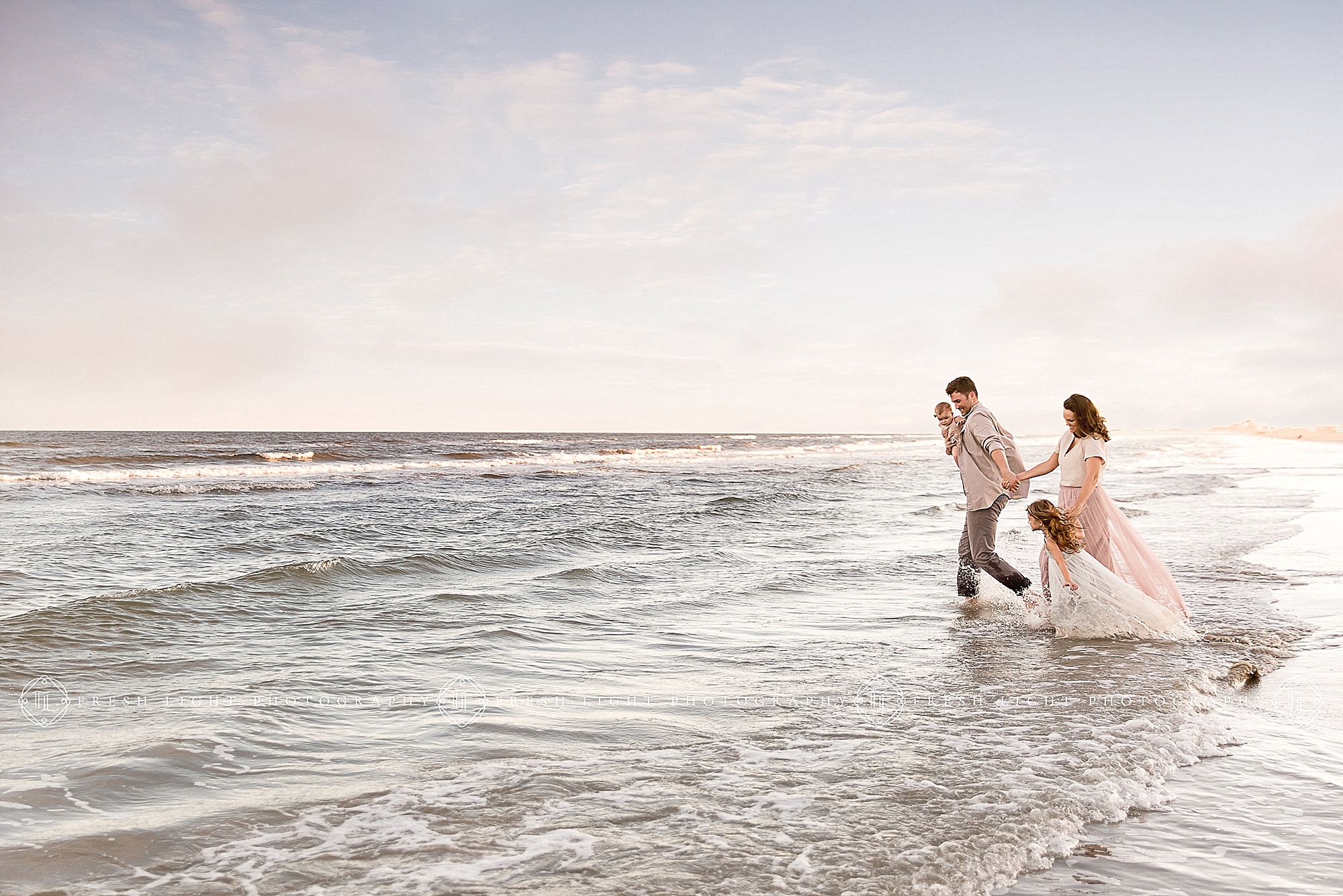 Family wading in the water on the beach