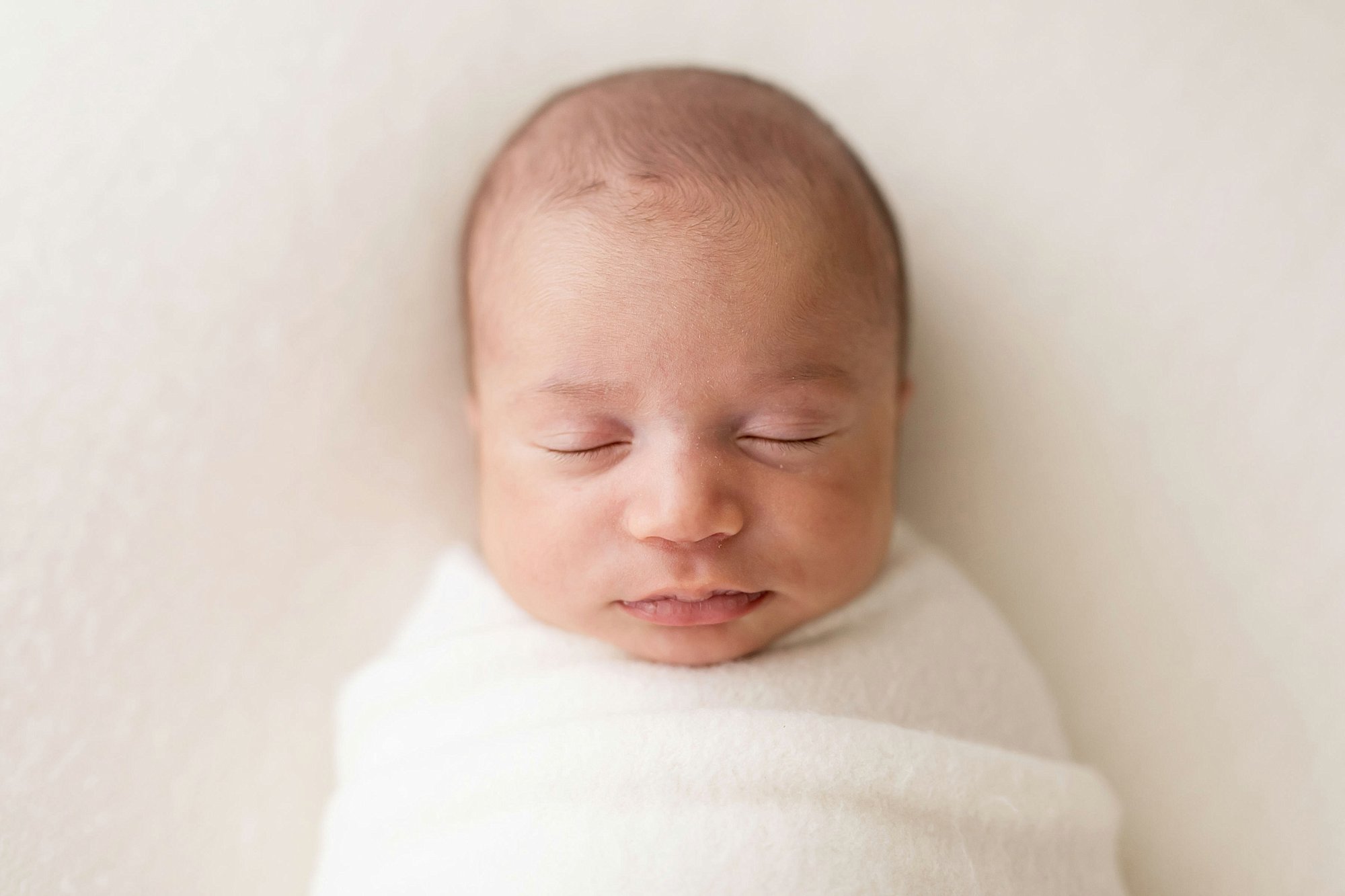 close up of newborn baby on white blanket