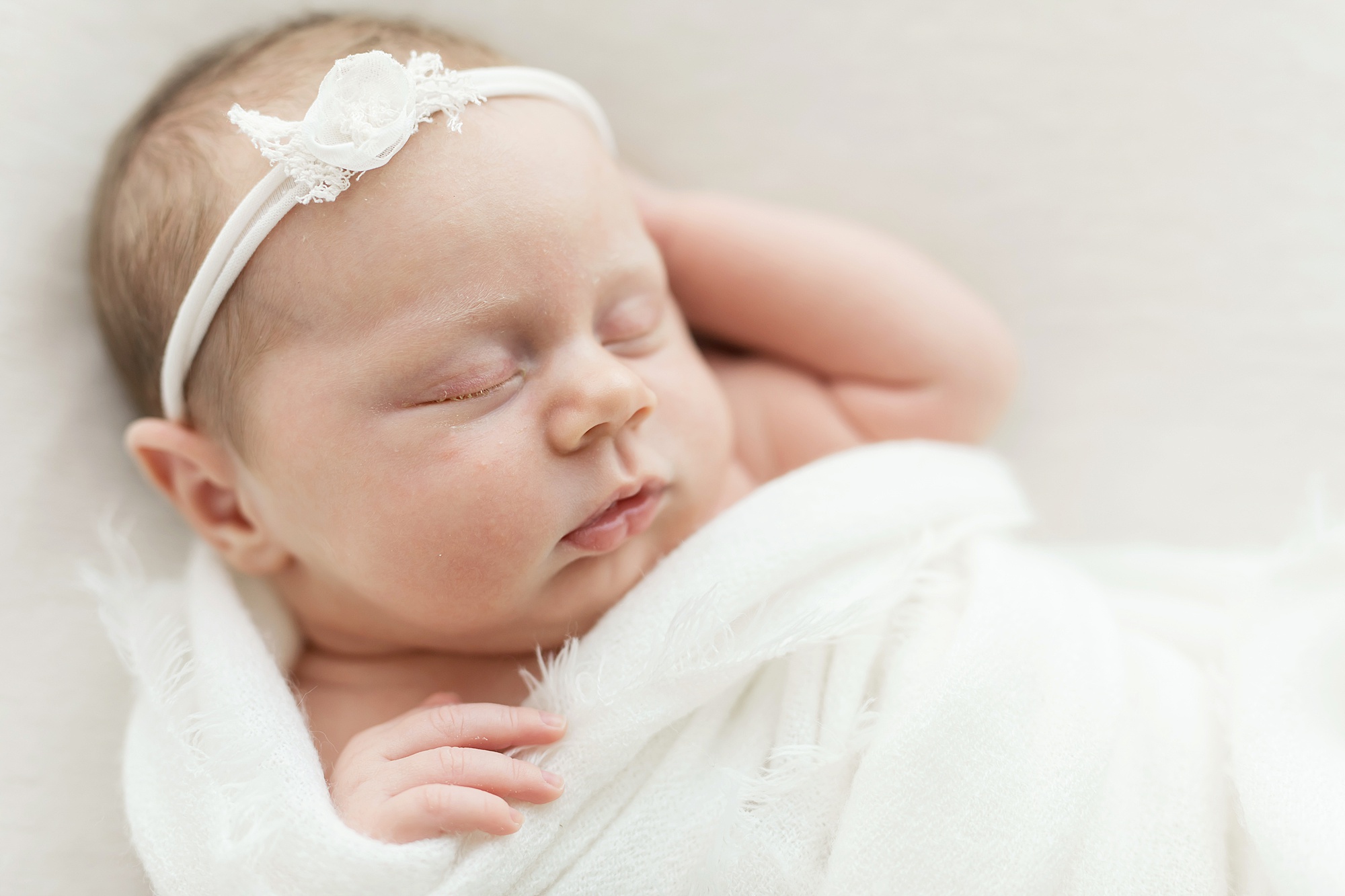 baby girl with arms out of white swaddle