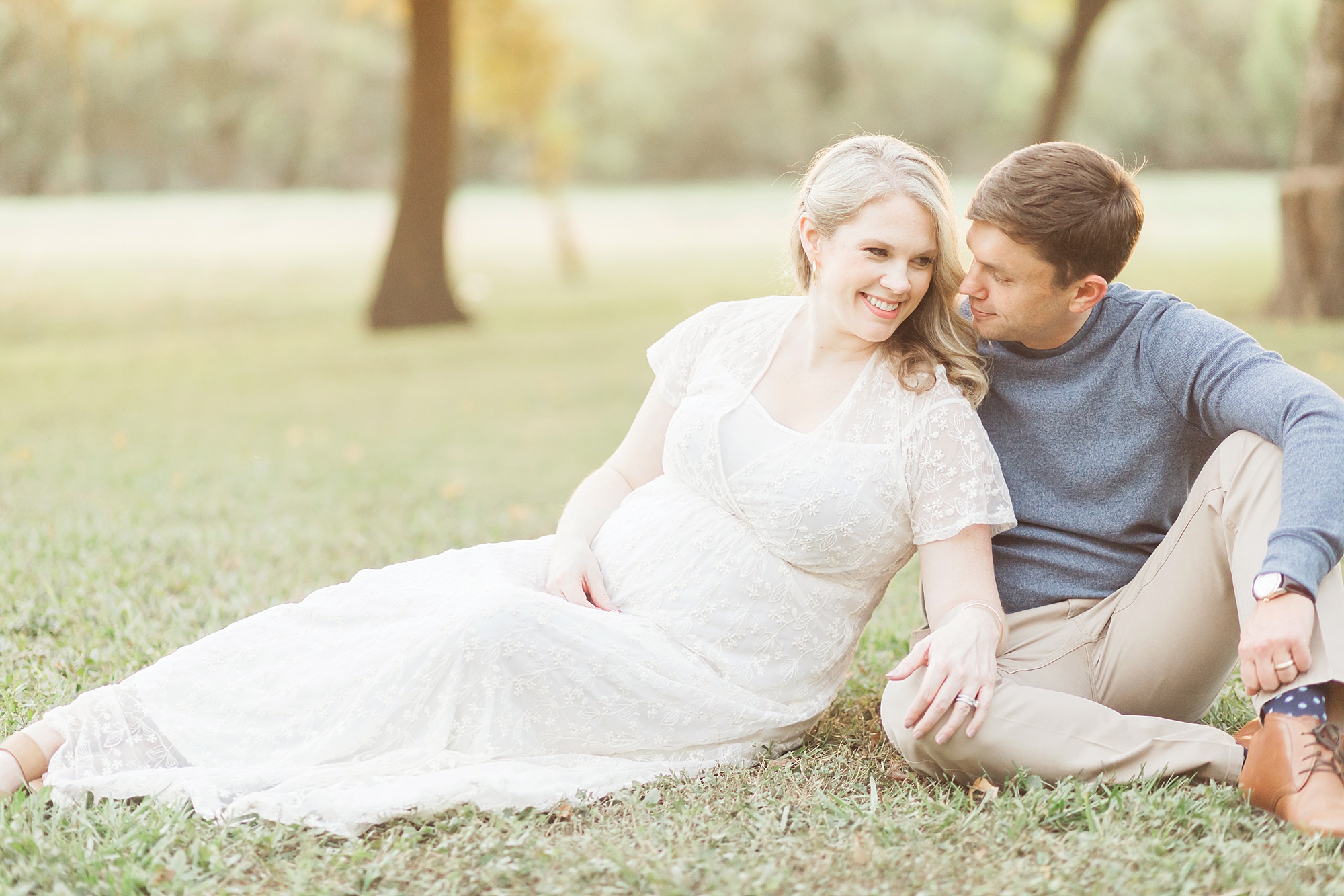 couple sitting on the grass for pregnancy pictures
