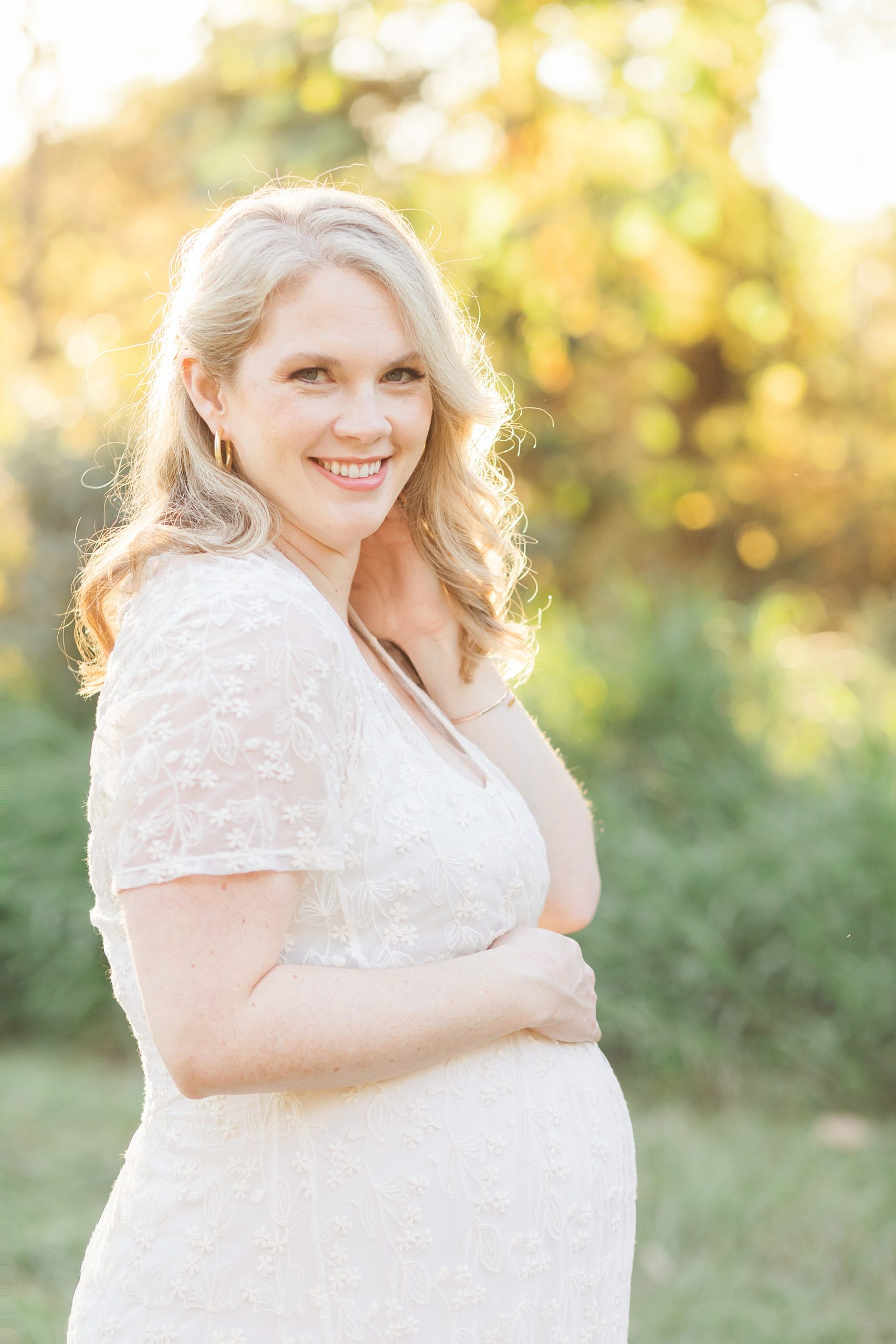 mom in white dress taking maternity pictures