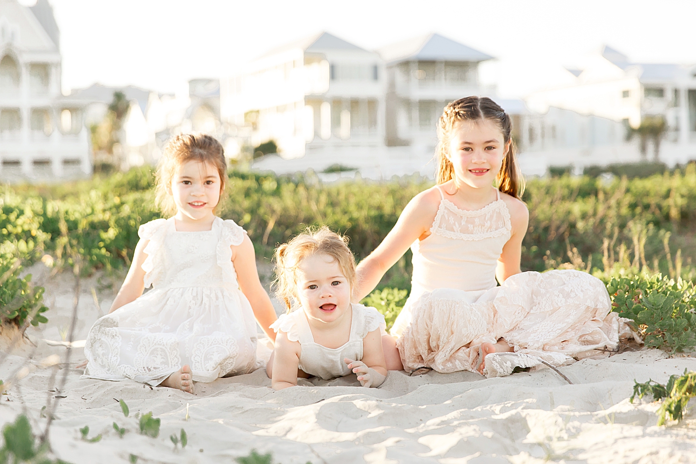 Three girls sitting on the sand in the dunes at Galveston Beach. Photos by Fresh Light Photography.