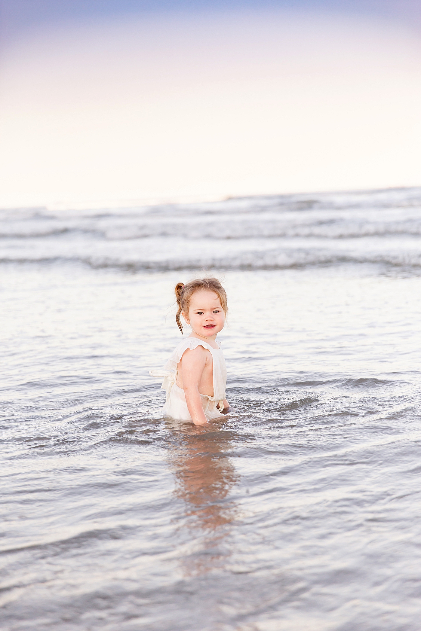 Toddler girl playing in the ocean during family photoshoot with Fresh Light Photography.