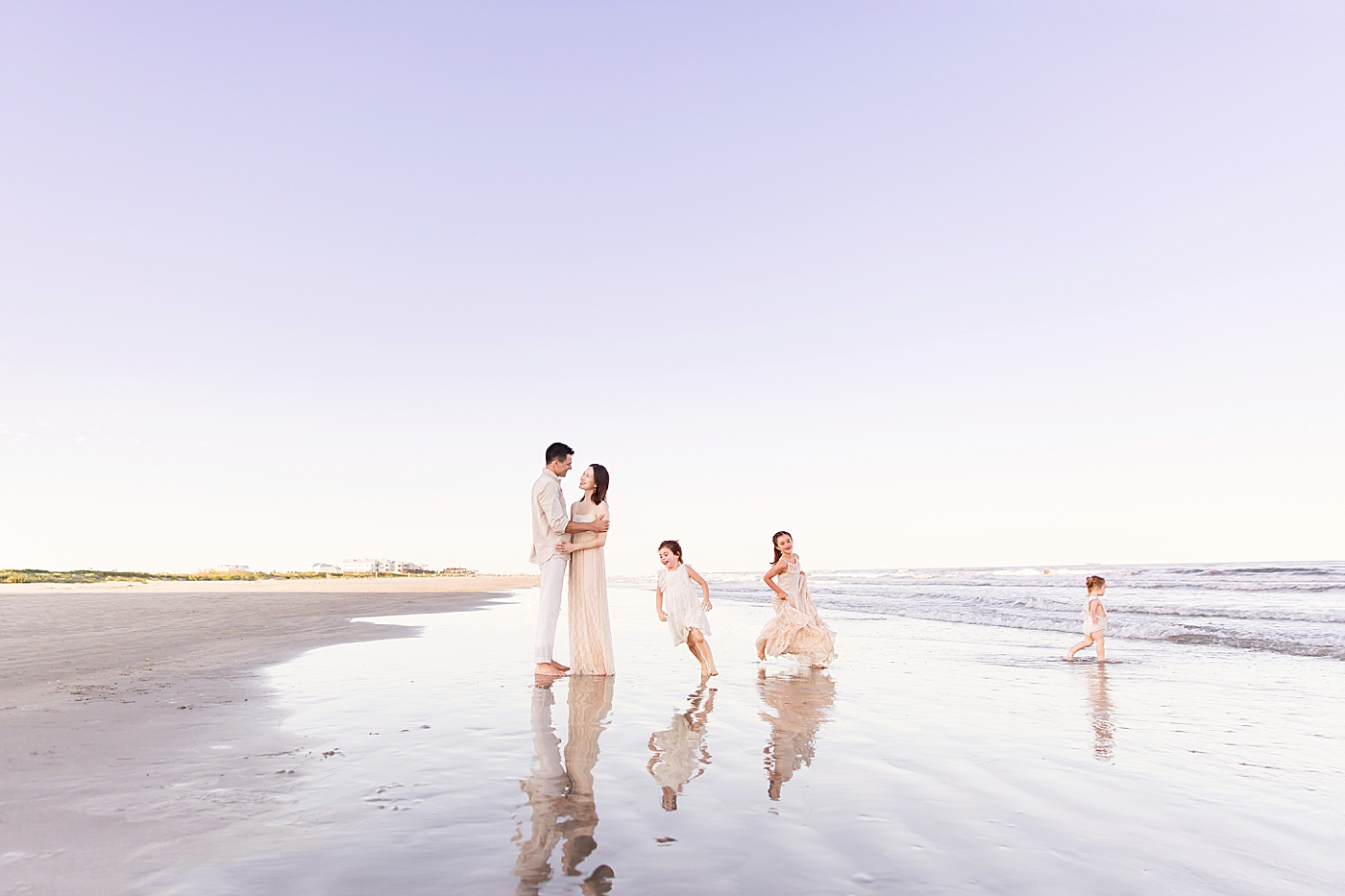 Three girls running around Mom and Dad during their Galveston Beach family session with Fresh Light Photography. 
