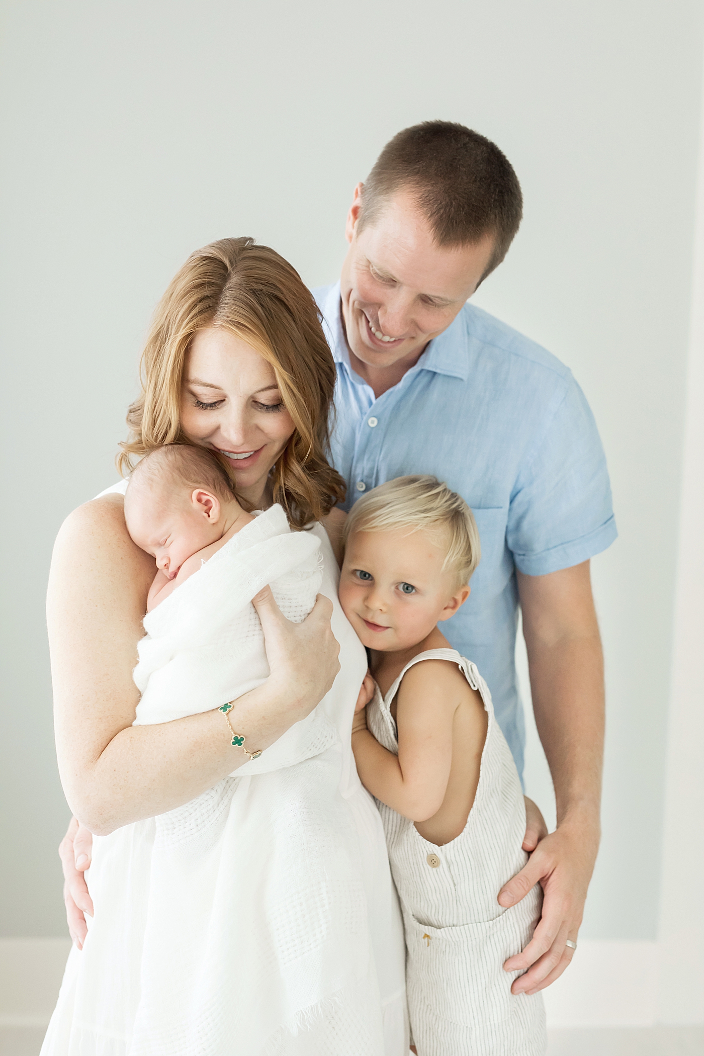 Family hugging during newborn photoshoot in a studio in the Heights. Photos by Fresh Light Photography and tips for how to prepare for your newborn session. 