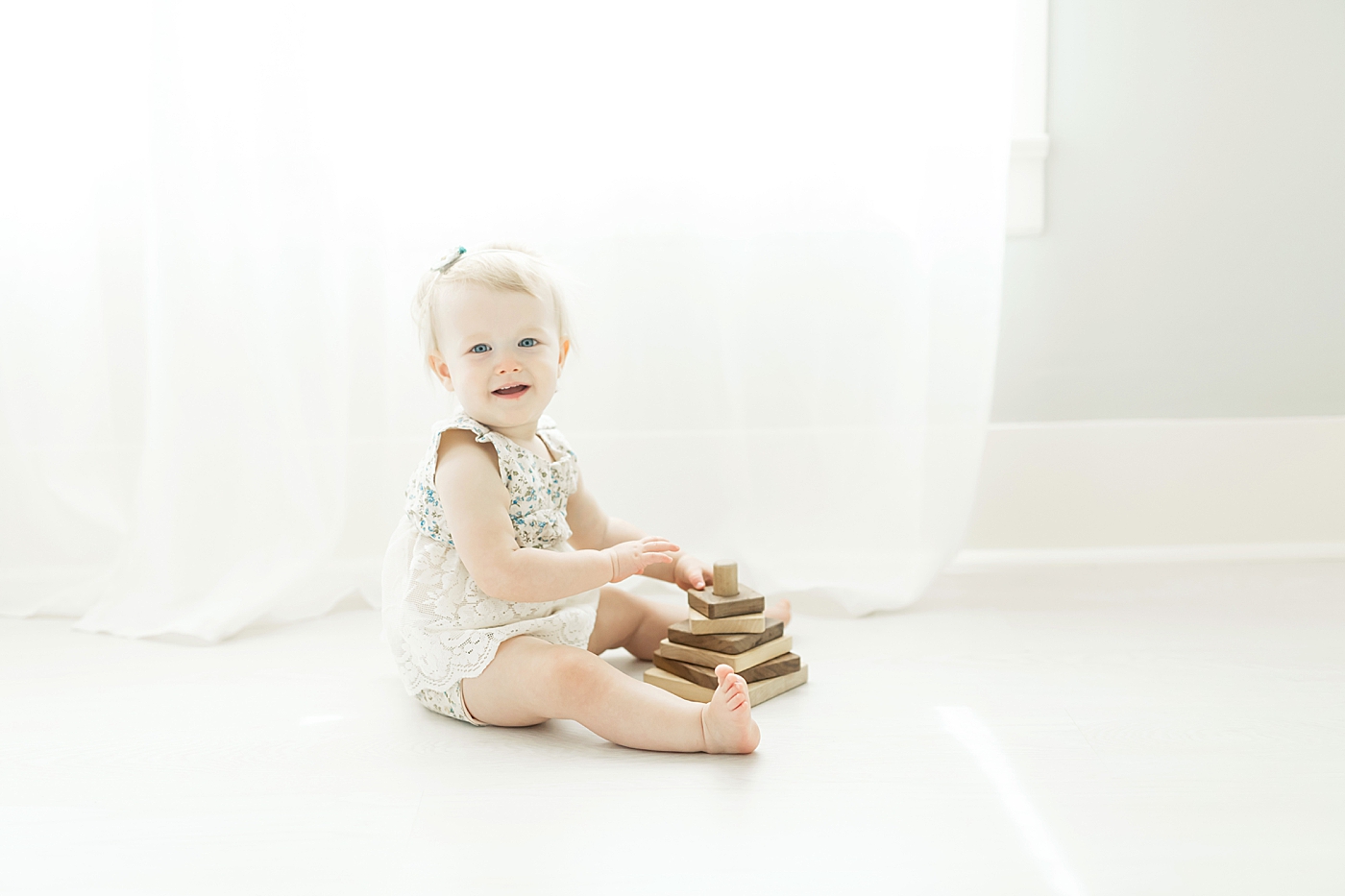 One year old playing with wooden stacker toy. Photo by Fresh Light Photography.