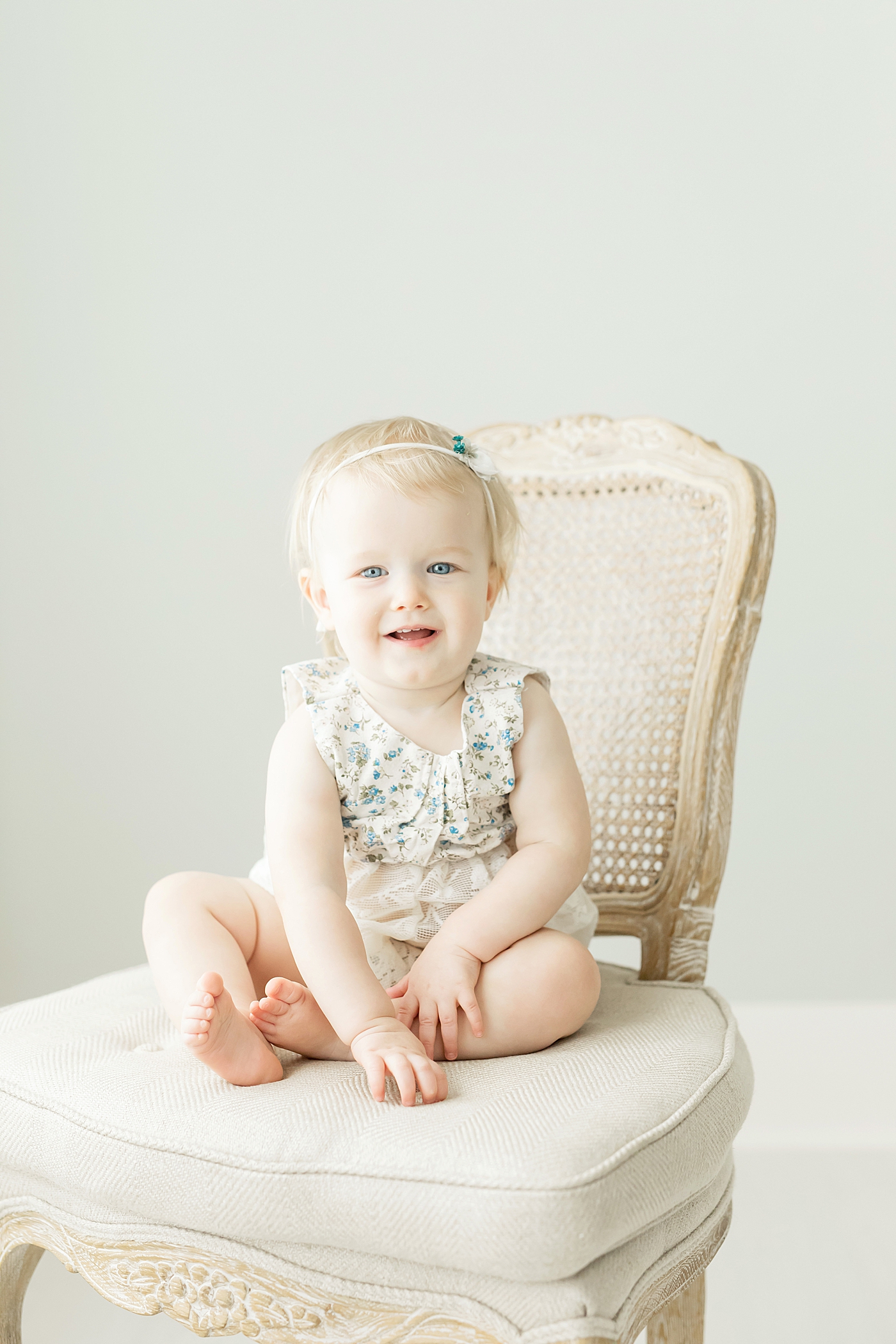 Baby girl sitting on a beautiful chair. Photo by Fresh Light Photography.