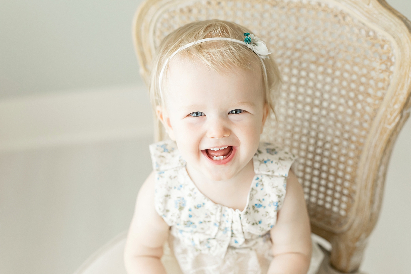 Baby girl smiling and wearing a floral romper. Photo by Fresh Light Photography.