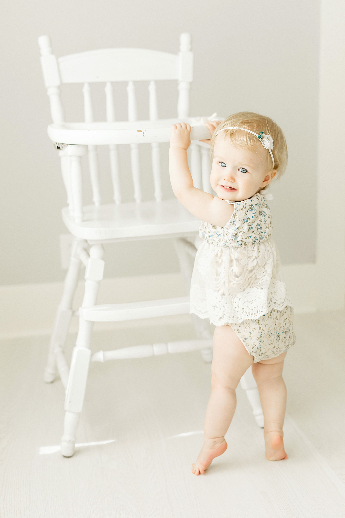 Baby girl holding onto white highchair during photoshoot with Fresh Light Photography in Houston. 