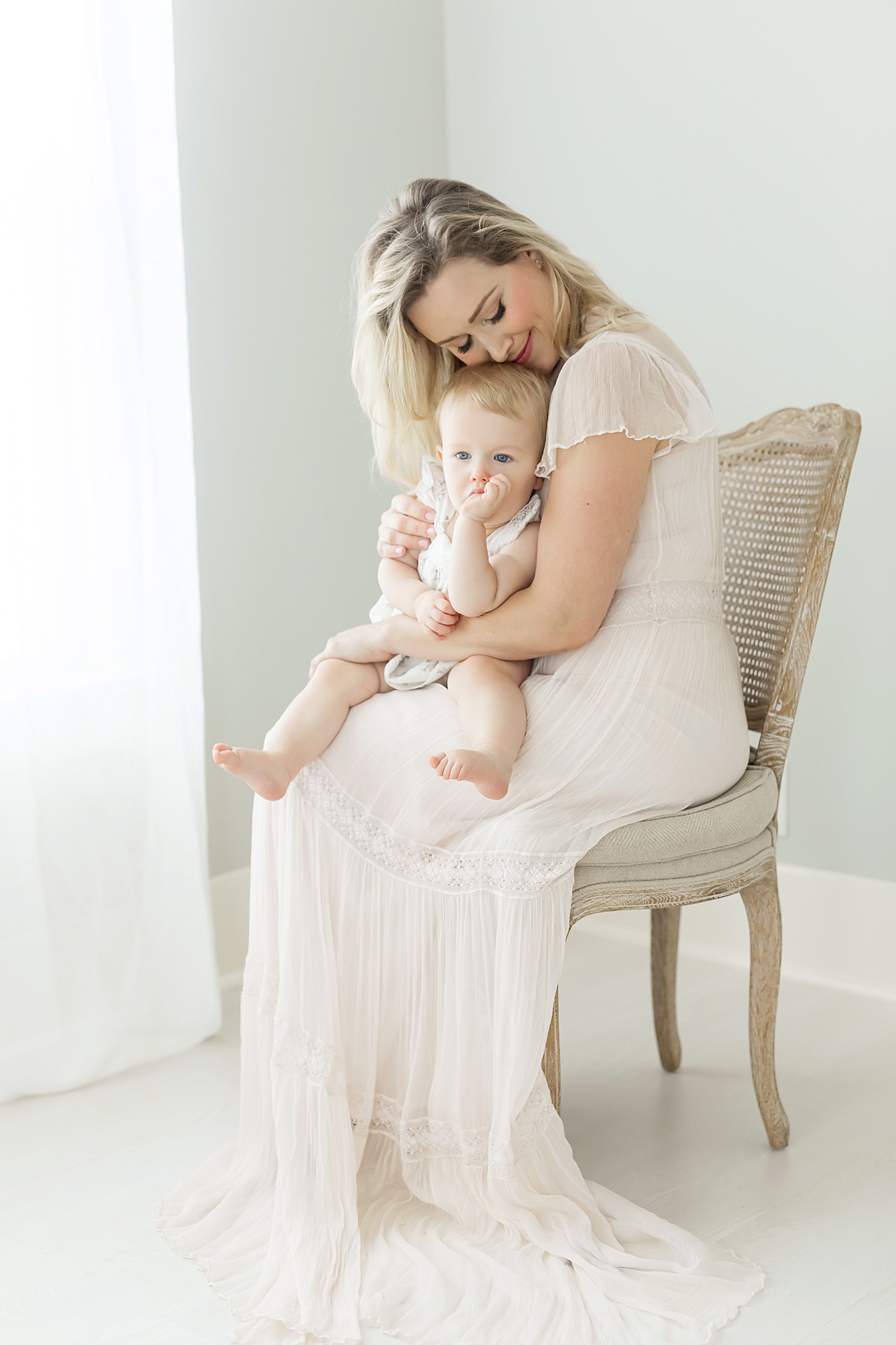 Mom snuggling her baby while she sucks her thumb. Photo by Fresh Light Photography.