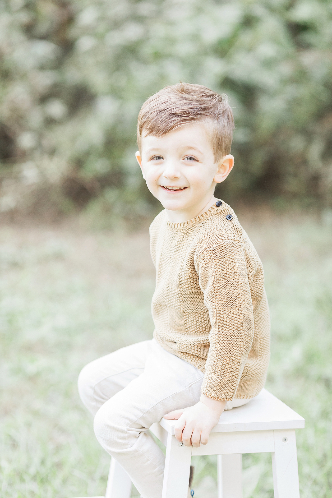 Children's portrait with young boy sitting on a stool smiling. Photo by Fresh Light Photography