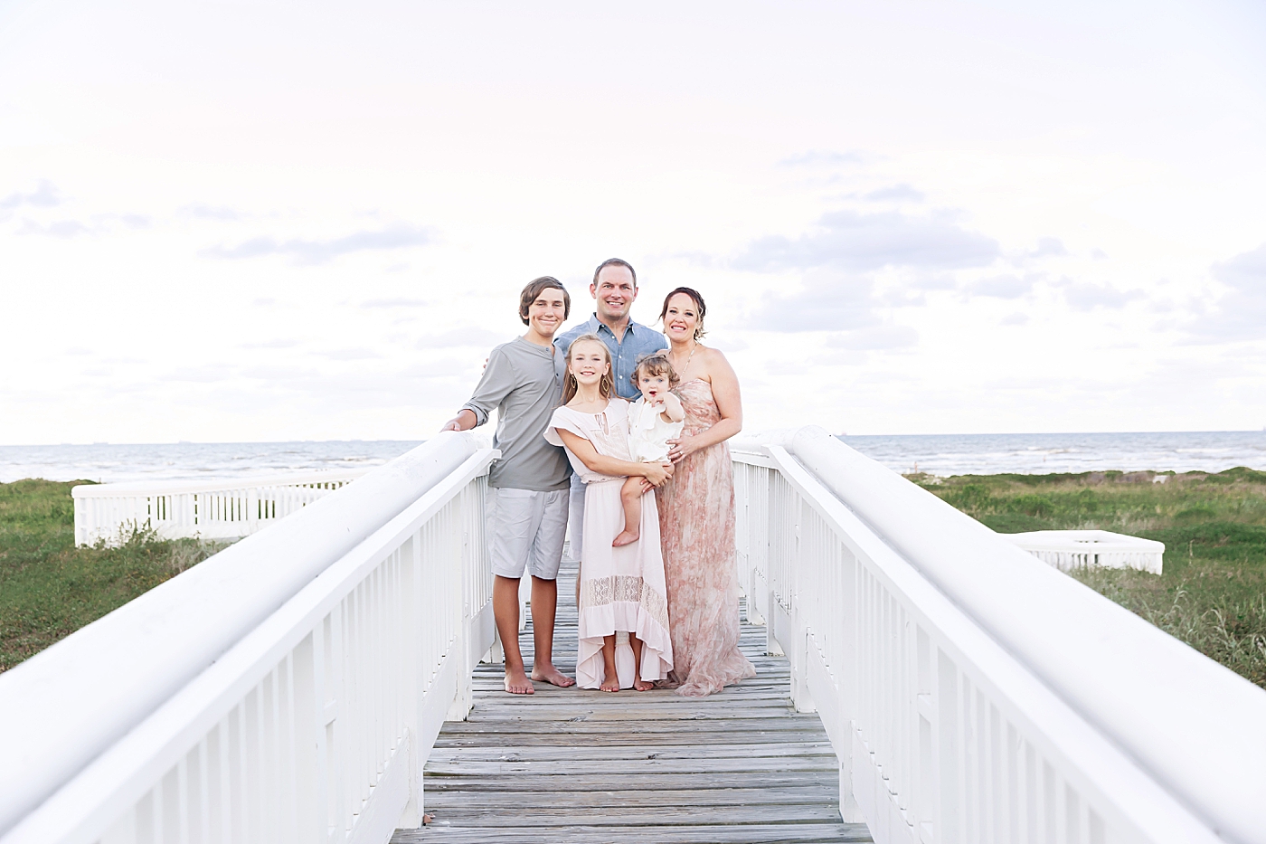 Family of five standing on walkway out to the beach at Galveston. Photo by Fresh Light Photography.