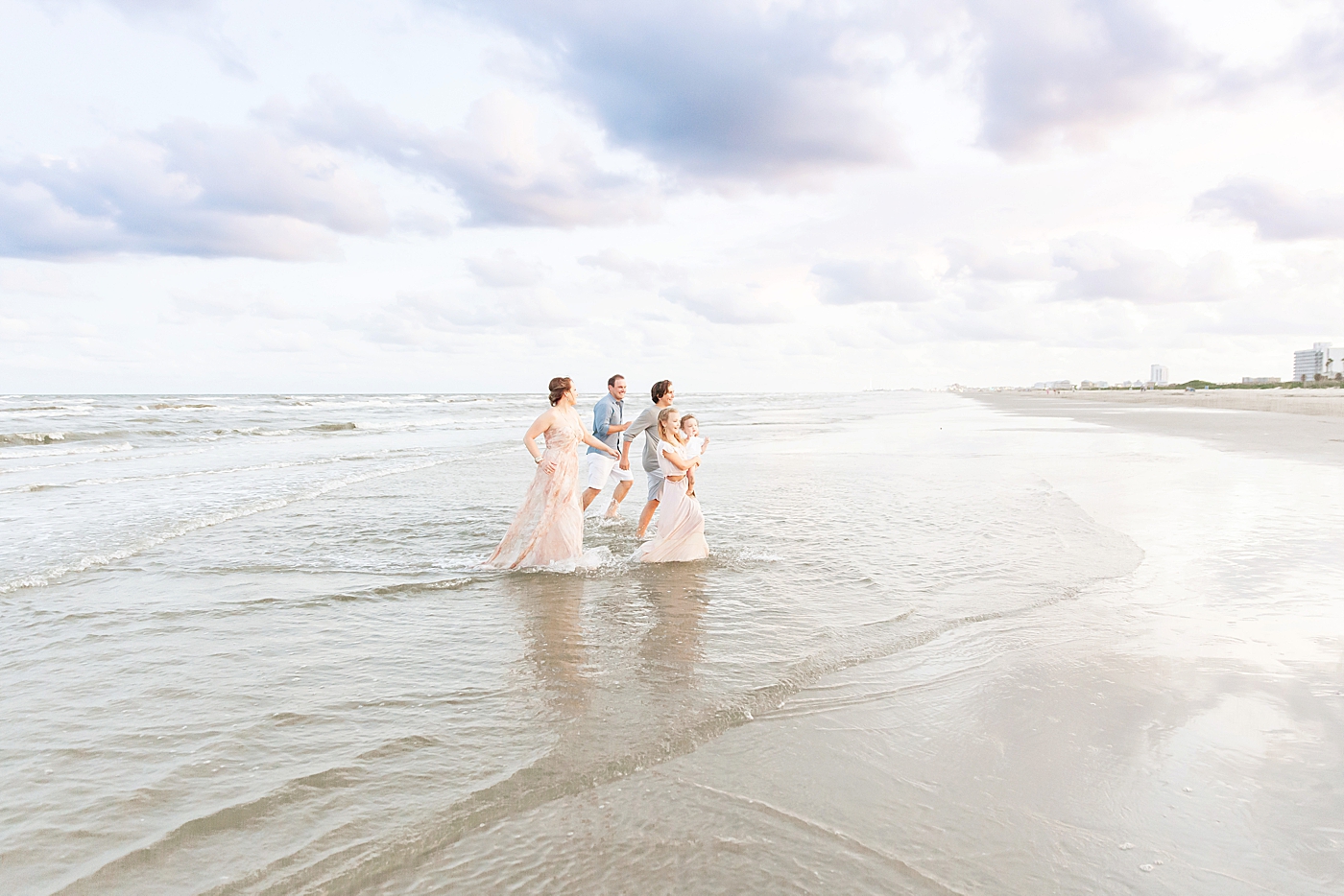 Family playing in the water during photos at Galveston Beach with Fresh Light Photography.