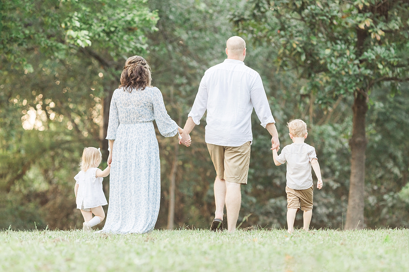 Family holding hands and walking during outdoor family pictures in Houston with Fresh Light Photography.