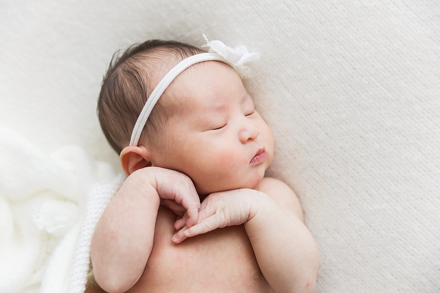 Baby girl with her hands curled up by her face. Photo by Fresh Light Photography.