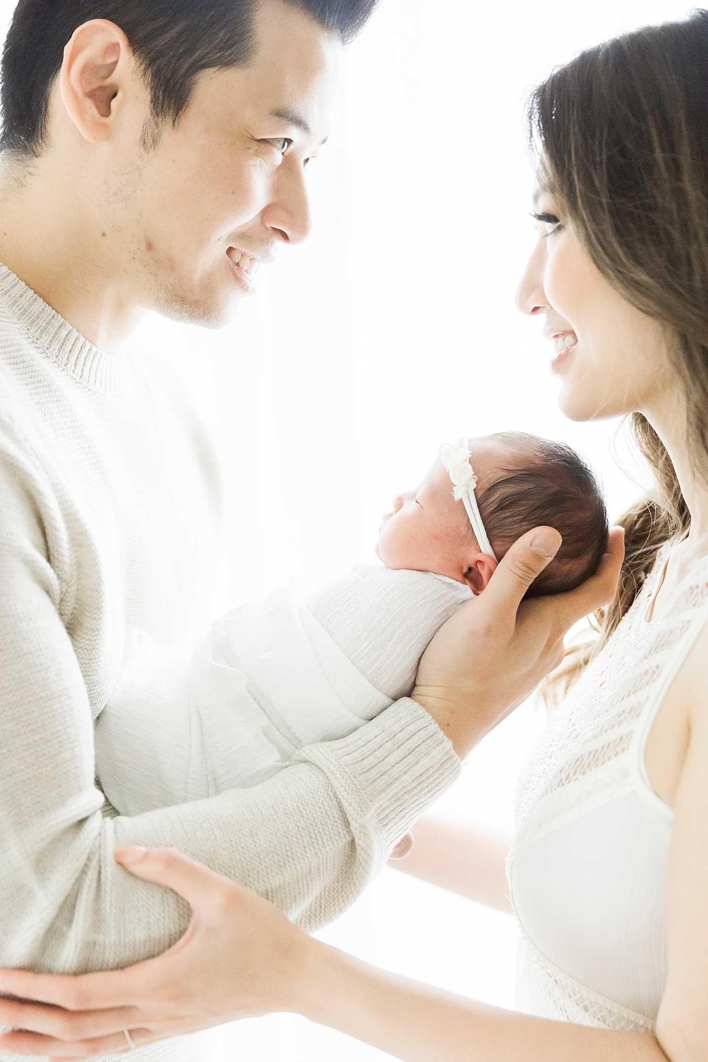 First time. parents looking at each other while holding their baby girl. Photo by Fresh Light Photography.
