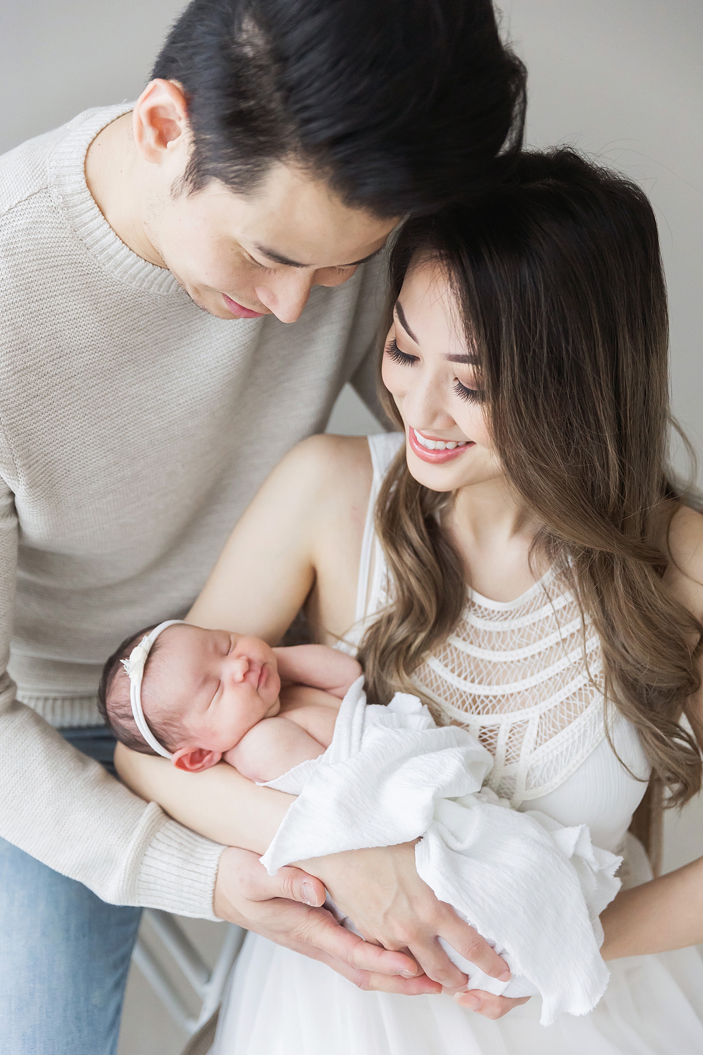 Parents holding their newborn baby girl. Photo by Fresh Light Photography and blog post sharing why professional newborn photography is so important.