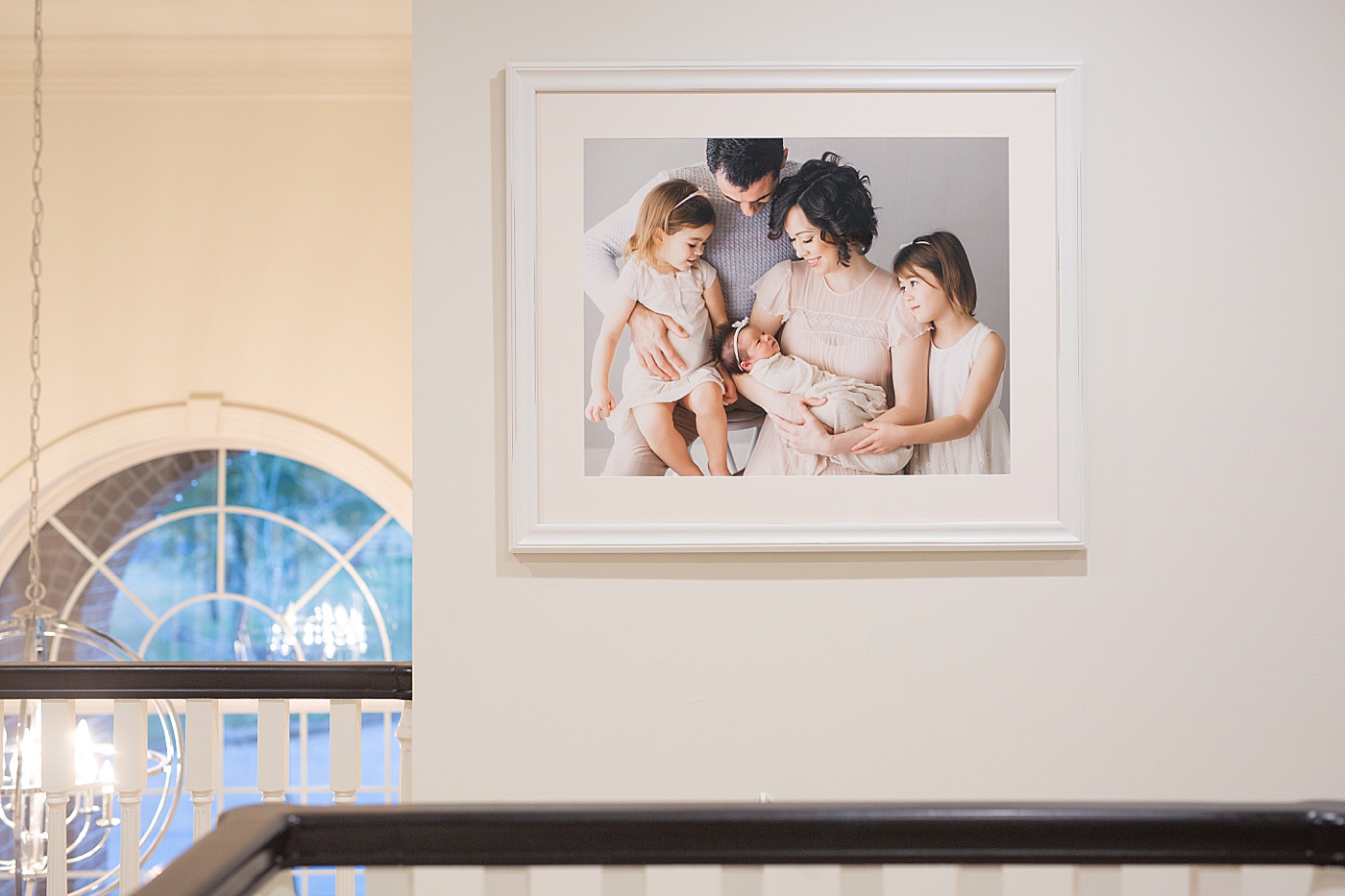 Large family photo at the top of the stairs. Custom framing and install by Fresh Light Photography.