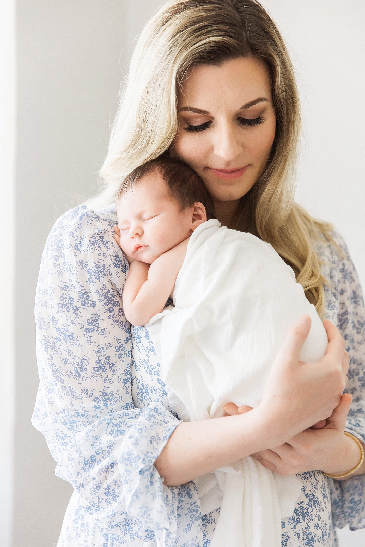 Mom holding sleeping baby on chest for newborn photos with Fresh Light Photography.