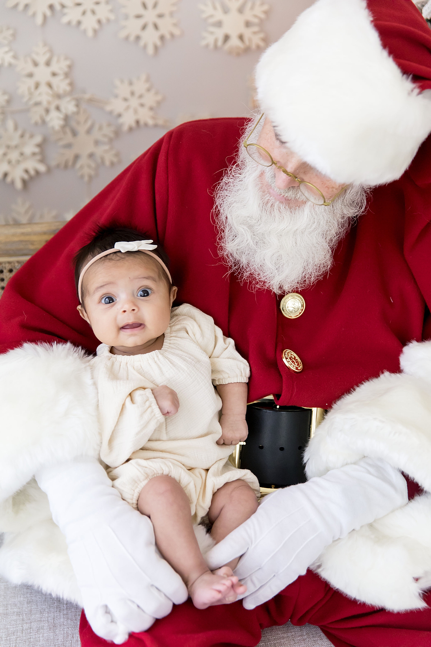 Baby girl sitting on Santa's lap at event held by Fresh Light Photography.