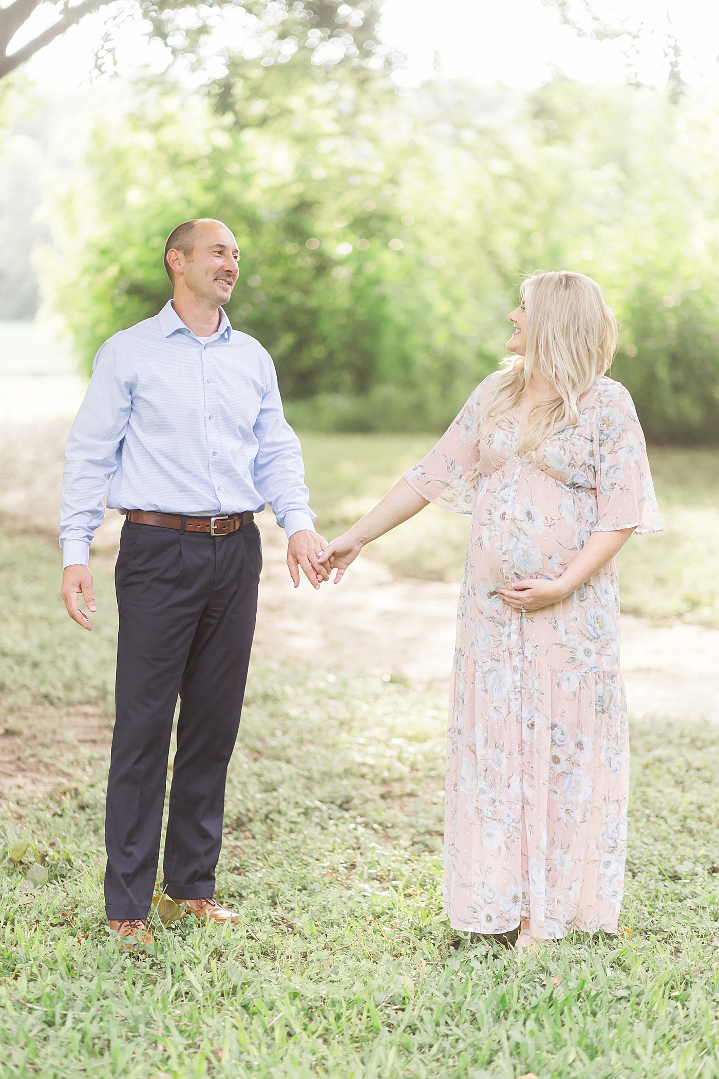 Parents holding hands, looking at each other during maternity photos with Fresh Light Photography.