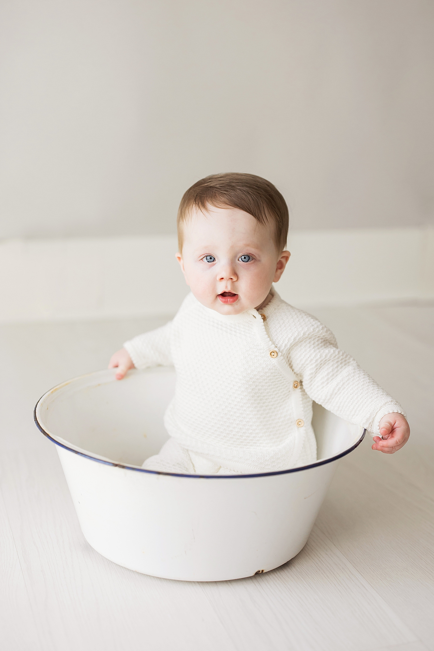 Baby boy wearing knit outfit sitting in big bowl. Photo by Fresh Light Photography