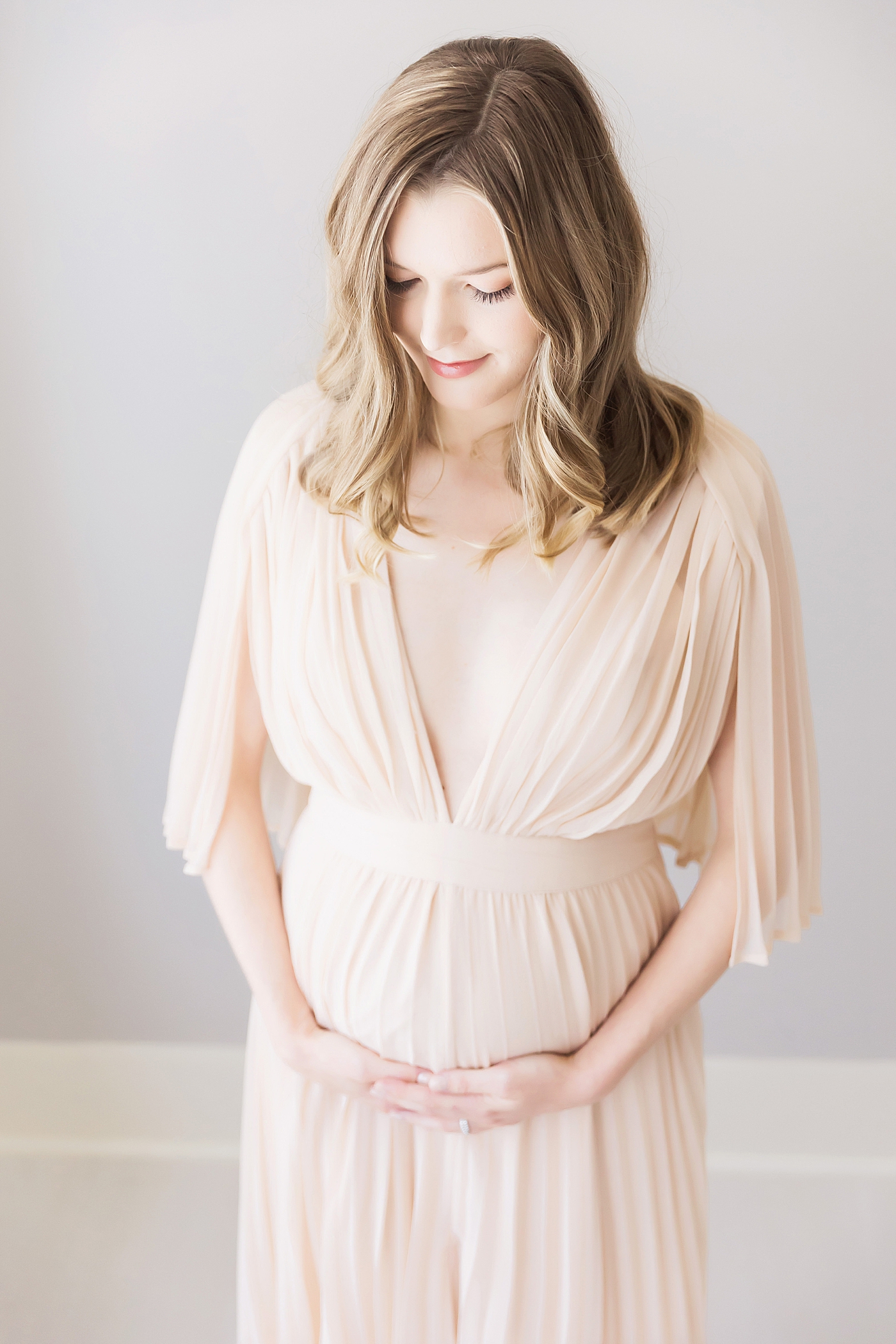 Expecting mom in beautiful dress holding her belly. Photo by Fresh Light Photography.