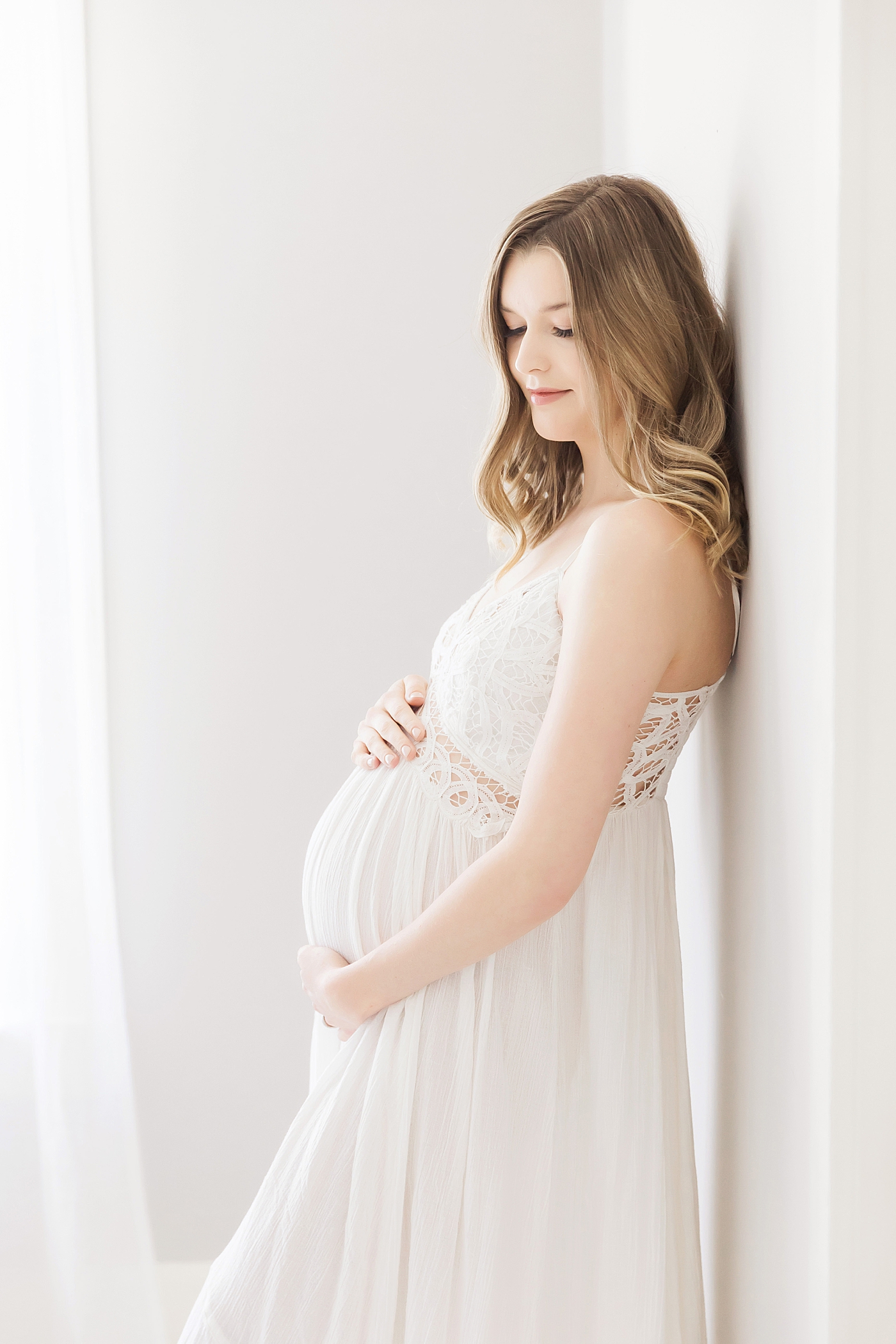Mom in white lace dress for pregnancy photos. Photo by Fresh Light Photography.