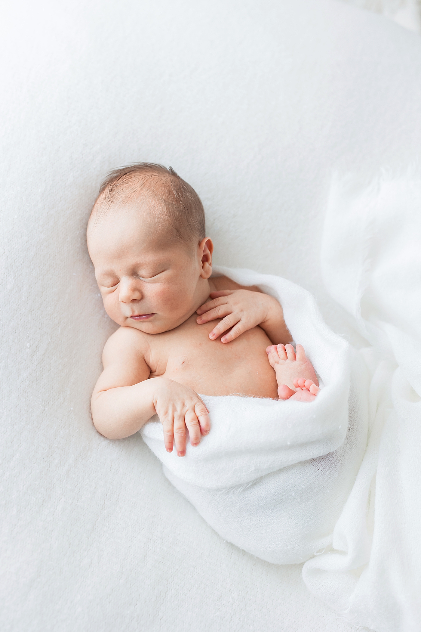 Baby boy curled up on his back and swaddled for newborn photos. Photos by Fresh Light Photography.