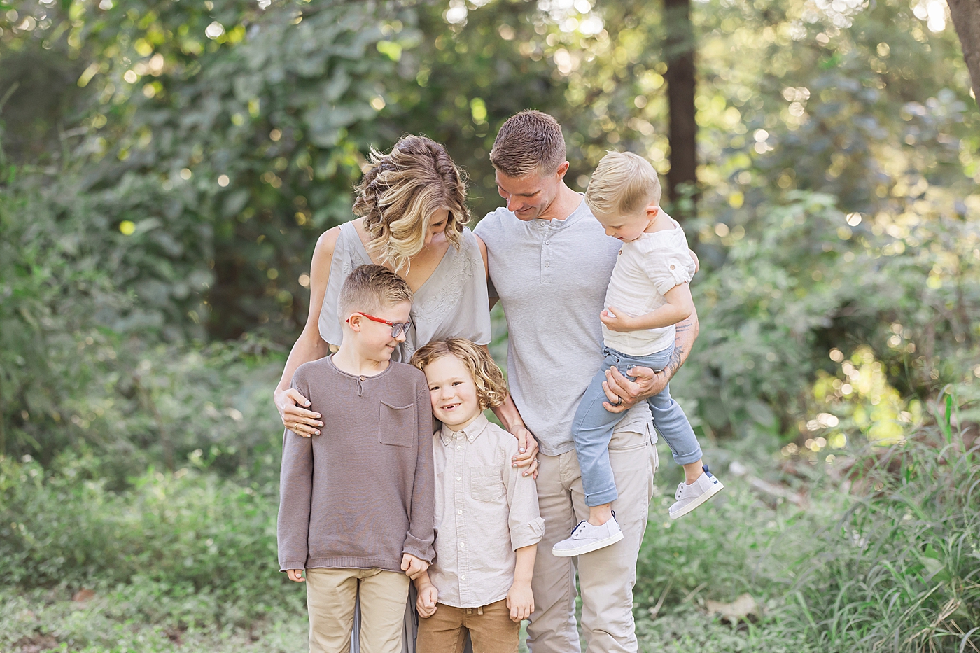 Mom, dad and their three boys standing in field for family photos with Fresh Light Photography