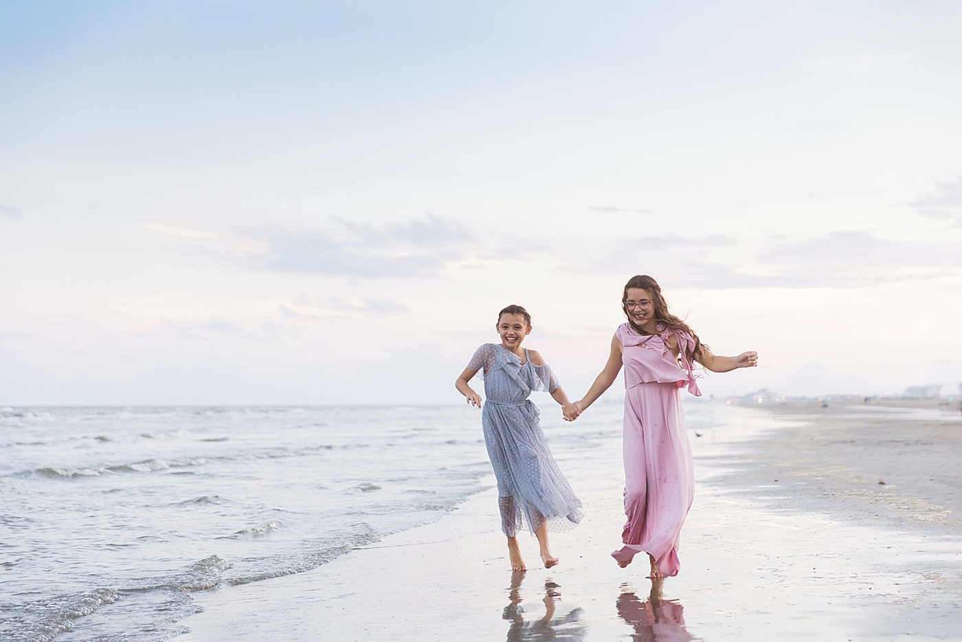 Sisters playing in the water together on Galveston beach. Photo by Fresh Light Photography.