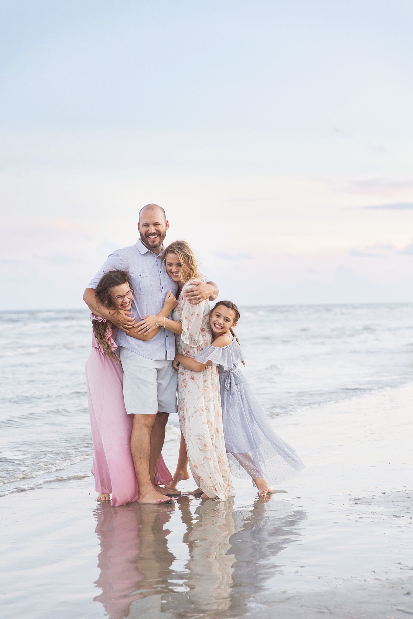 Family hugging during photoshoot on the beach. Photo by Fresh Light Photography.