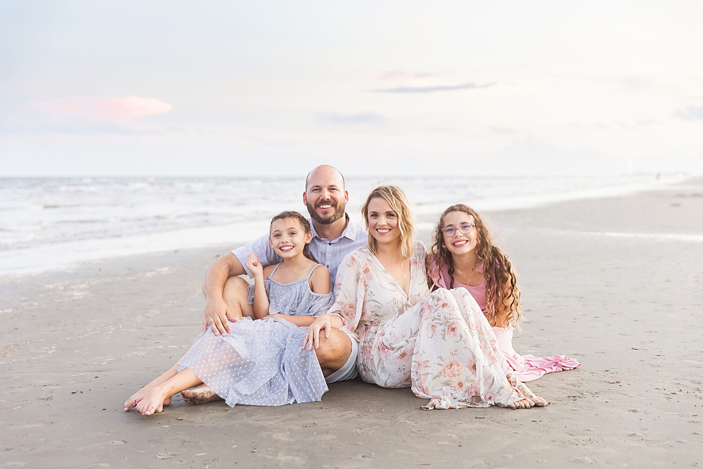 Family sitting on the beach during photoshoot with Fresh Light Photography in Galveston.