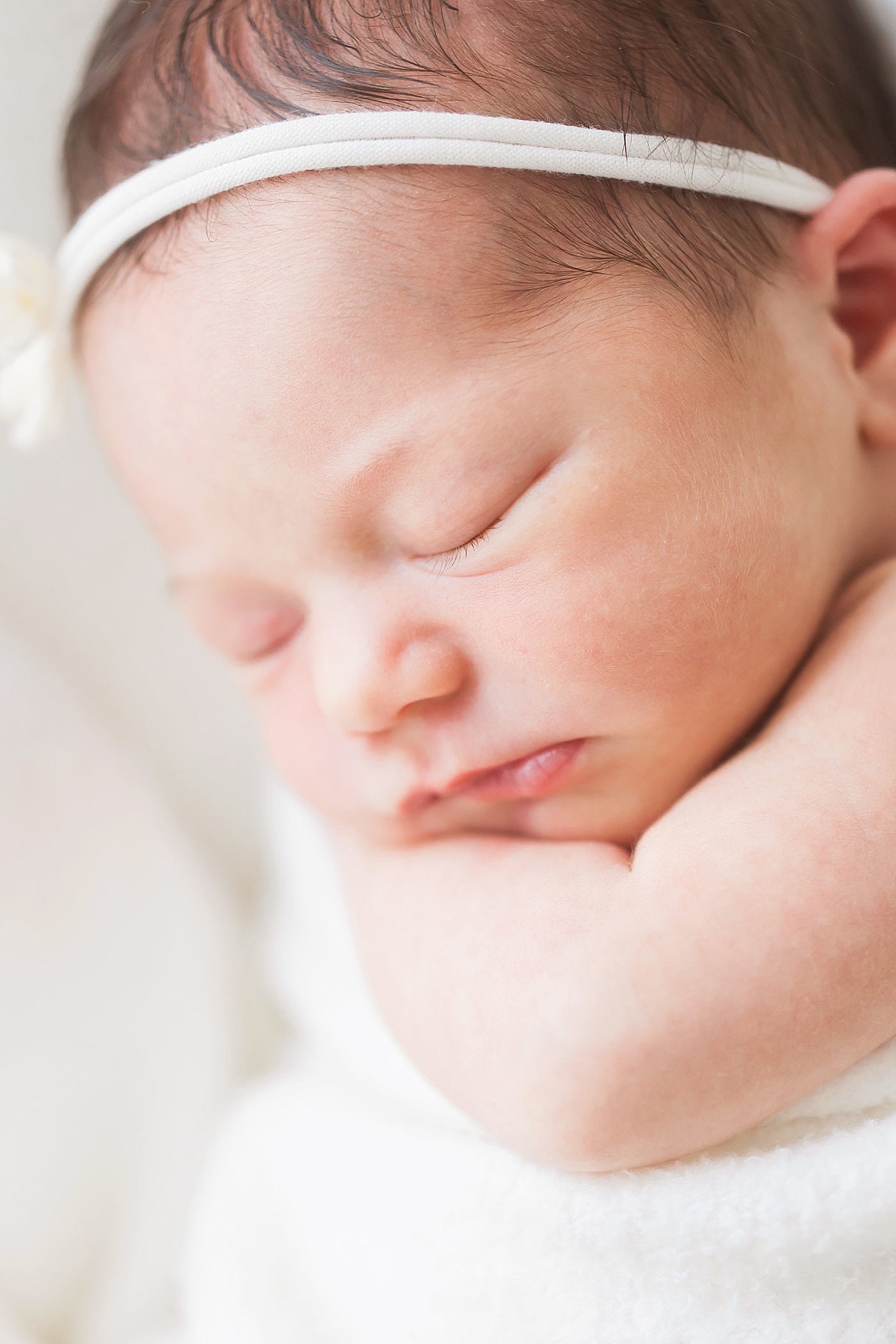 Baby girl curled up on her arm for newborn photos with Fresh Light Photography.