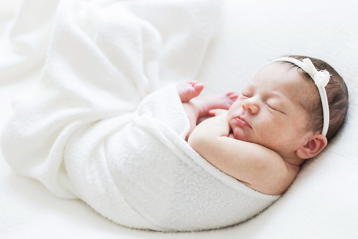 Baby girl swaddled and curled up for newborn photos with Fresh Light Photography.
