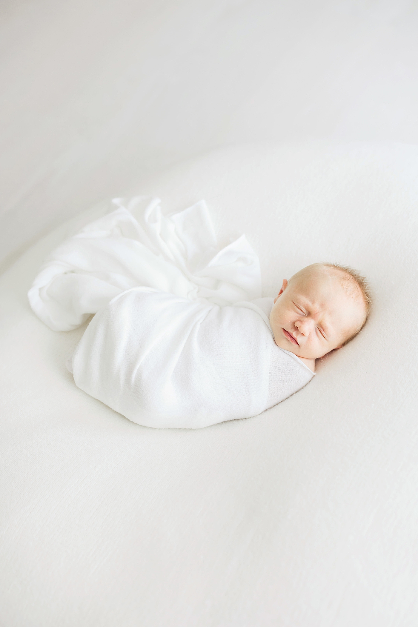 Baby boy swaddled in white for newborn session. Photo by Fresh Light Photography.