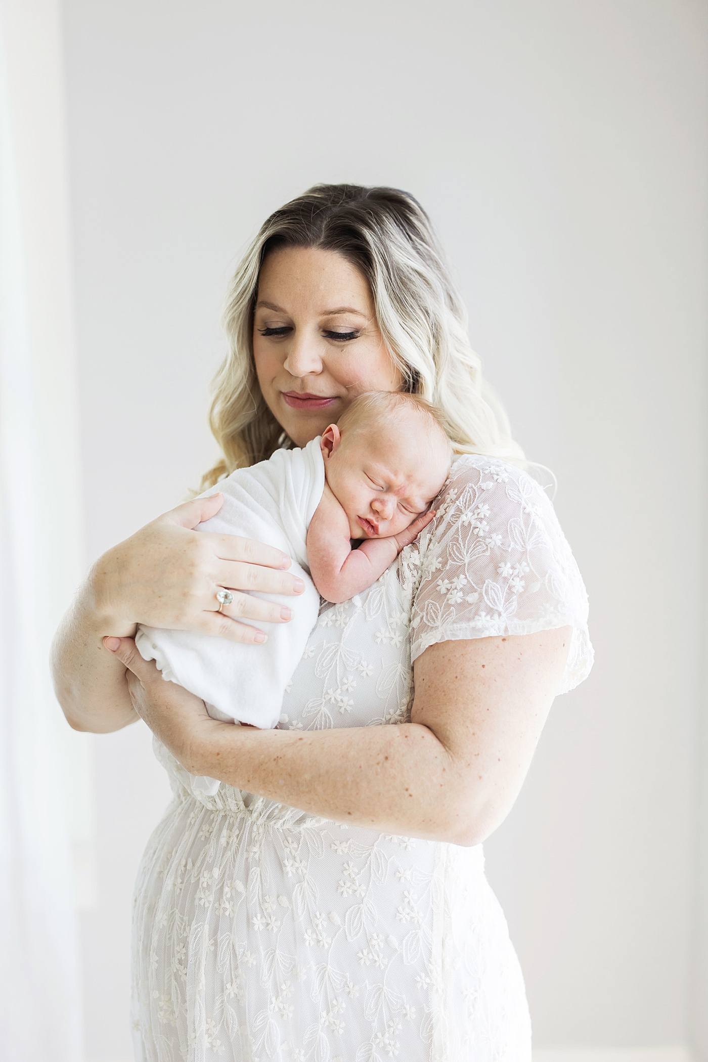 Baby boy curled up on Moms shoulder during newborn session. Photo by Fresh Light Photography.