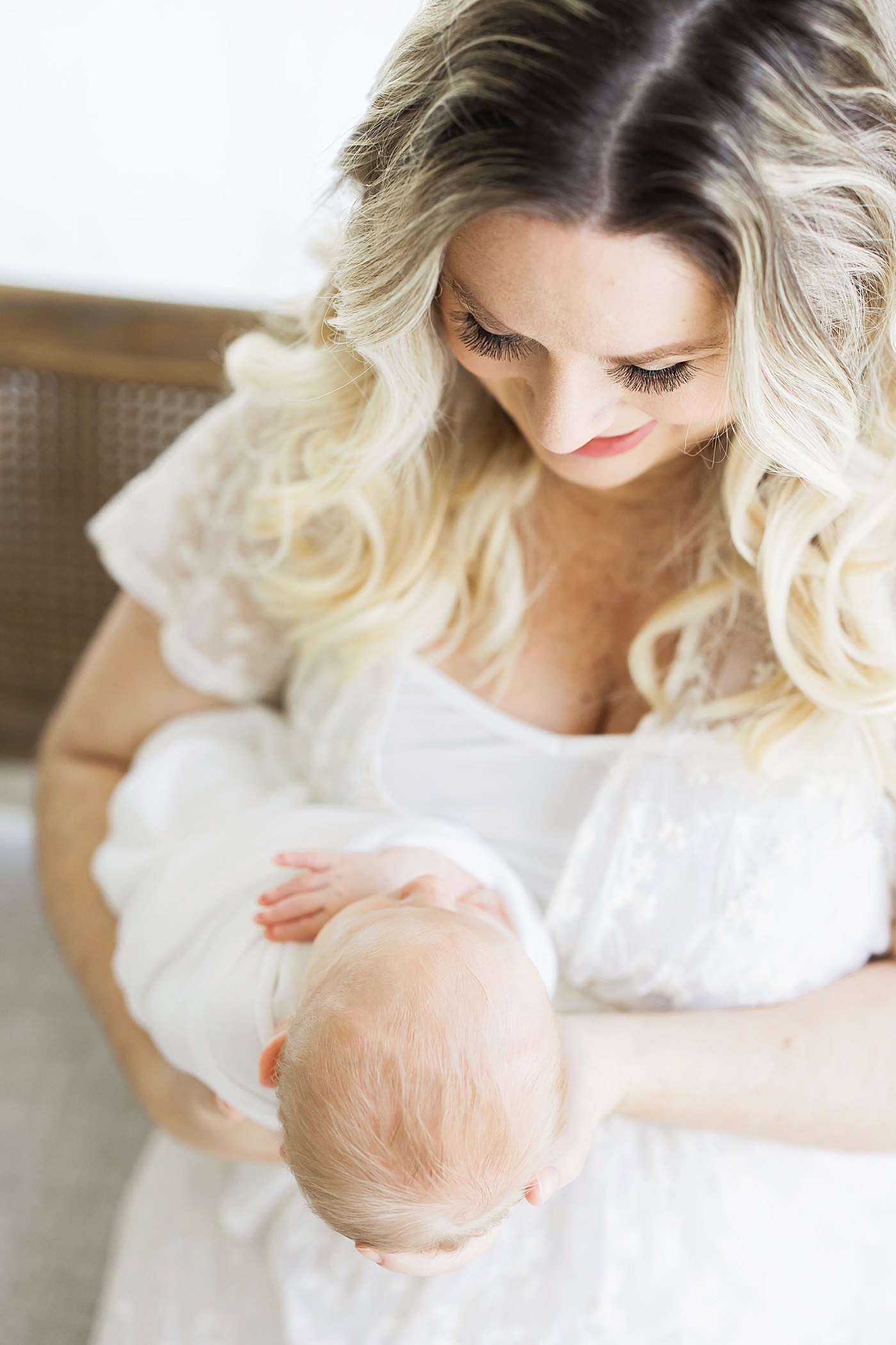 Mom holding her newborn son out in front of her, looking at him. Photo by Fresh Light Photography.